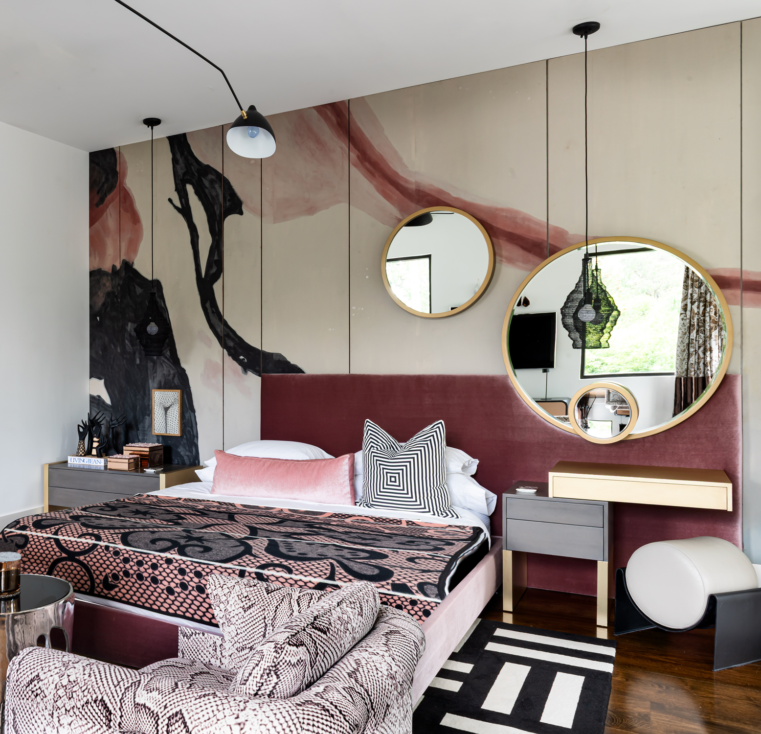Modern luxury home in Houston guest bedroom with a burgundy bed, graphic textiles, circular mirrors and mural wall.