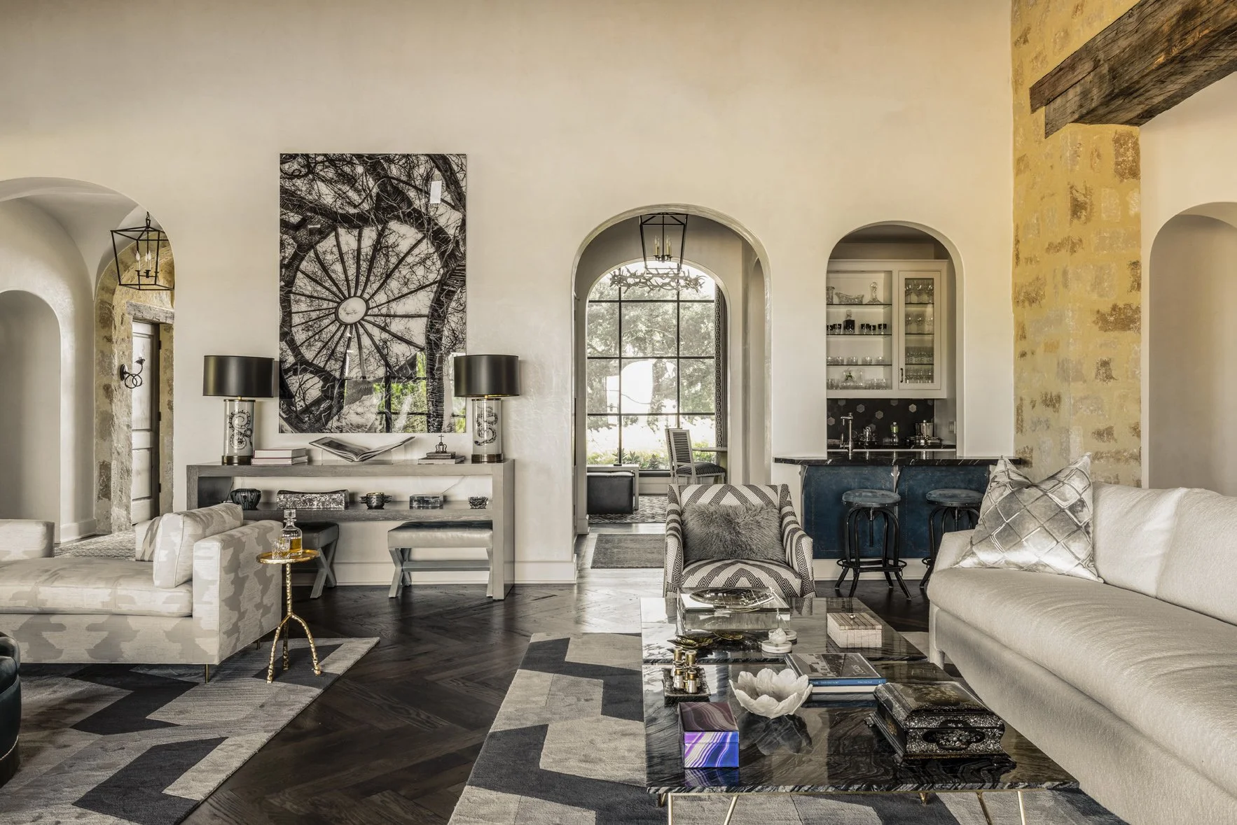 Modern ranch interior design with layered seating, graphic rugs, arched openings, contemporary art and a built-in bar.