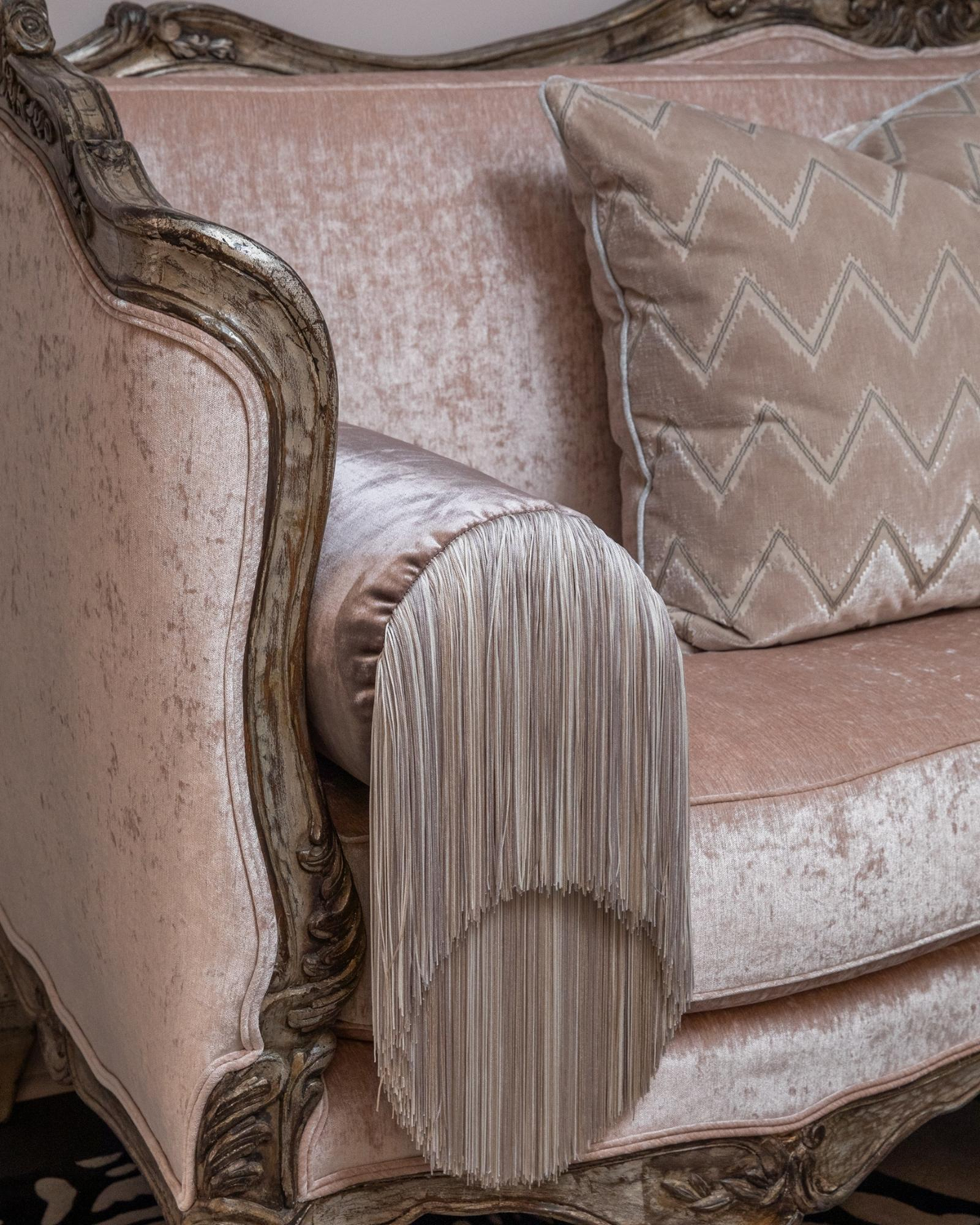 Wellness clinic Houston detail of an ornate blush chair with a long fringed bolster and geometric accent cushion.