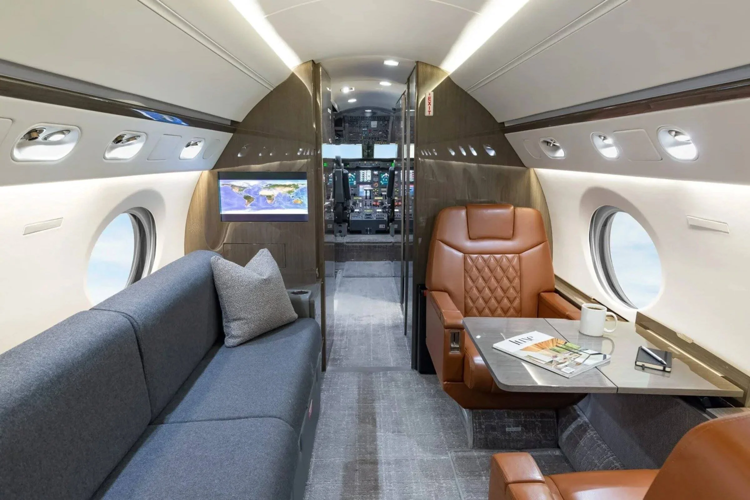 Commercial interior design project for a Gulfstream V business jet, with cognac leather seating, gray sofa and worktable.