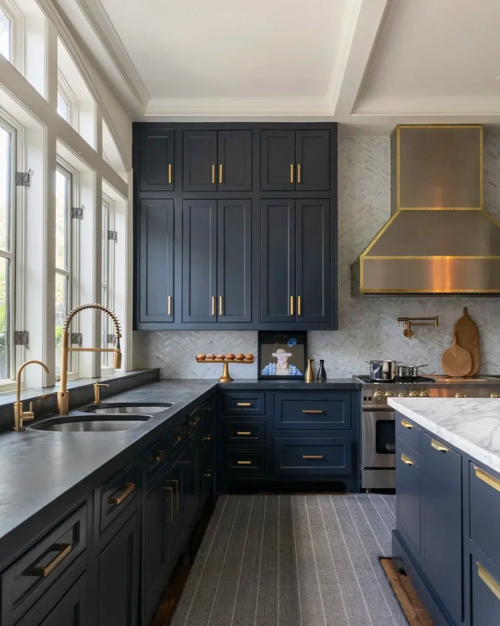 Classically inspired Houston luxury kitchen design featuring navy blue shaker-style cabinetry and brass handles