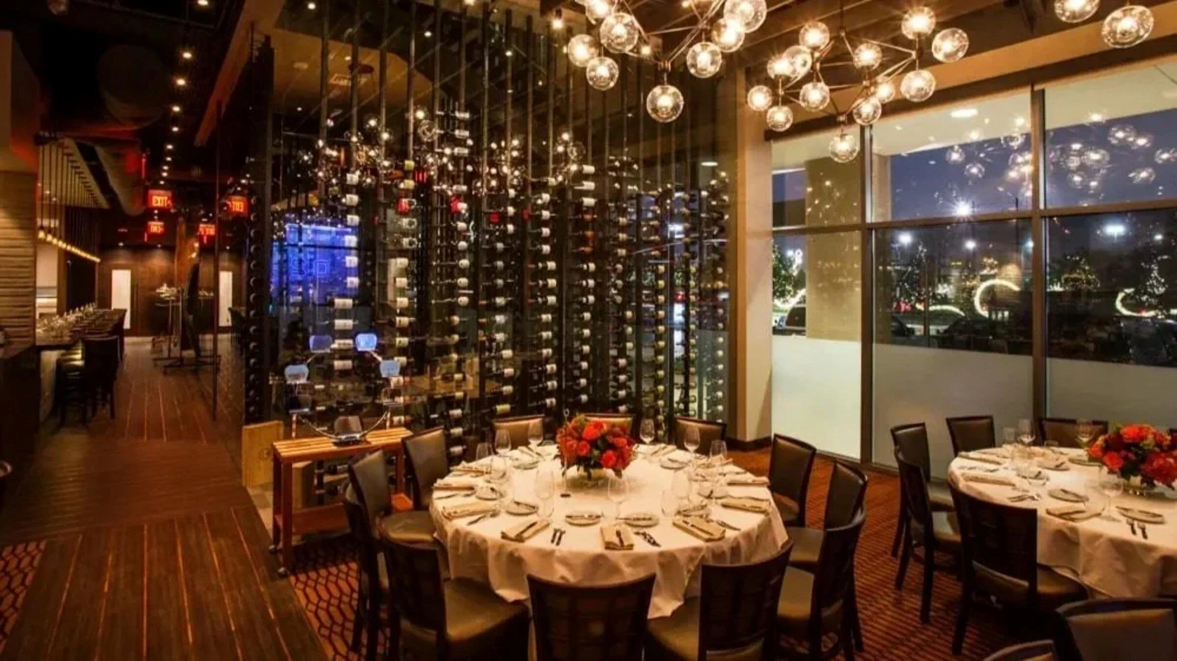 Vallone’s restaurant dining room with formal table settings, glass wine display and sculptural globe lighting.