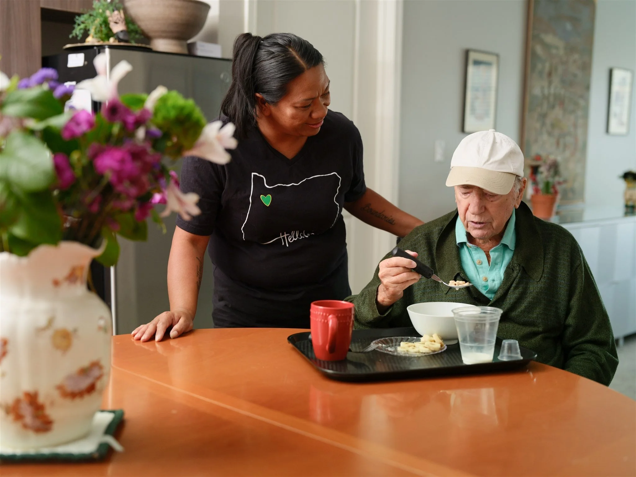 HelloCare caregiver providing meal assistance to an elderly man, helping him eat safely and comfortably at home.