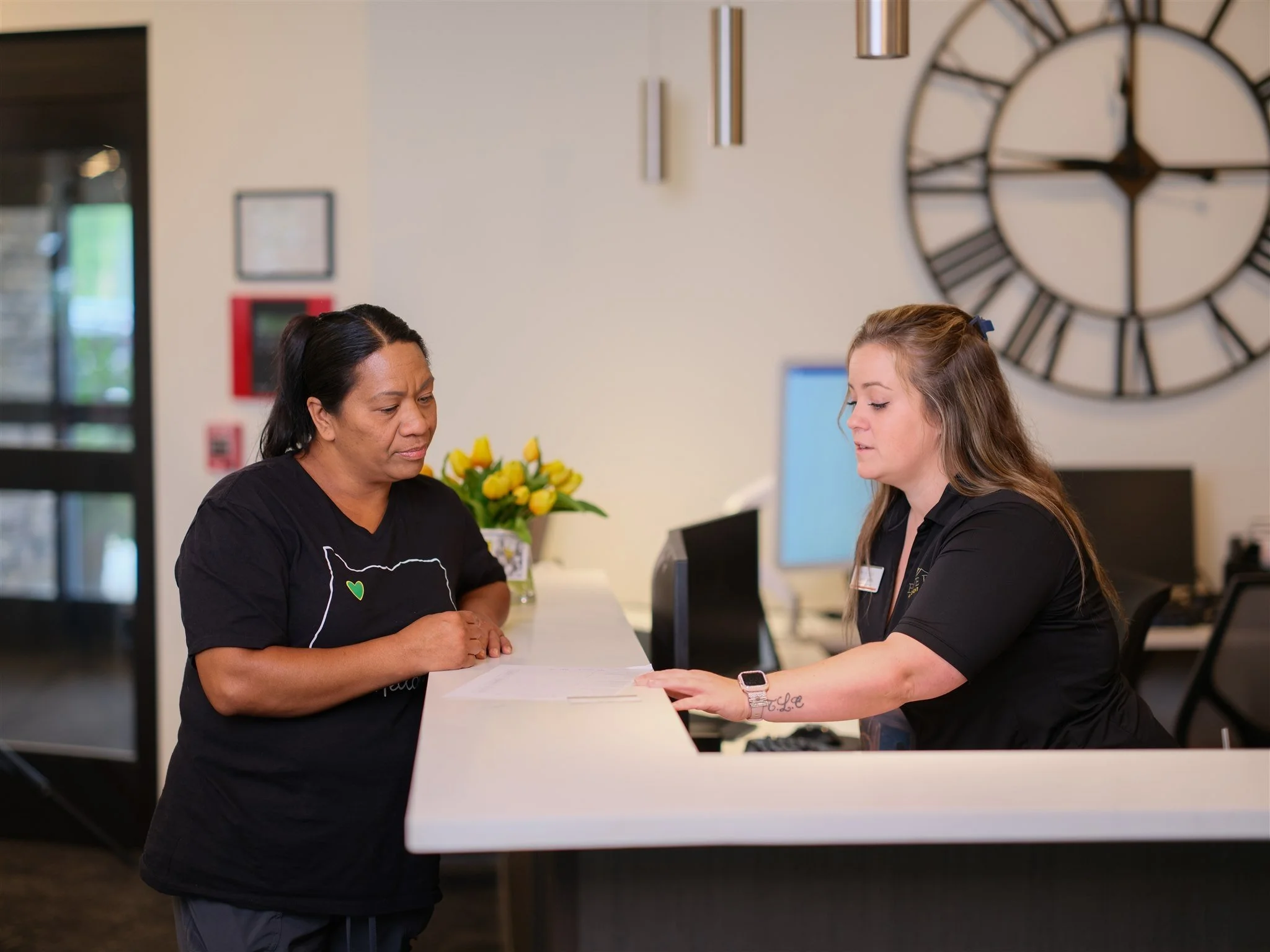 HelloCare caregiver coordinating with community staff at a reception desk, highlighting partnerships and resources that support seniors and families.