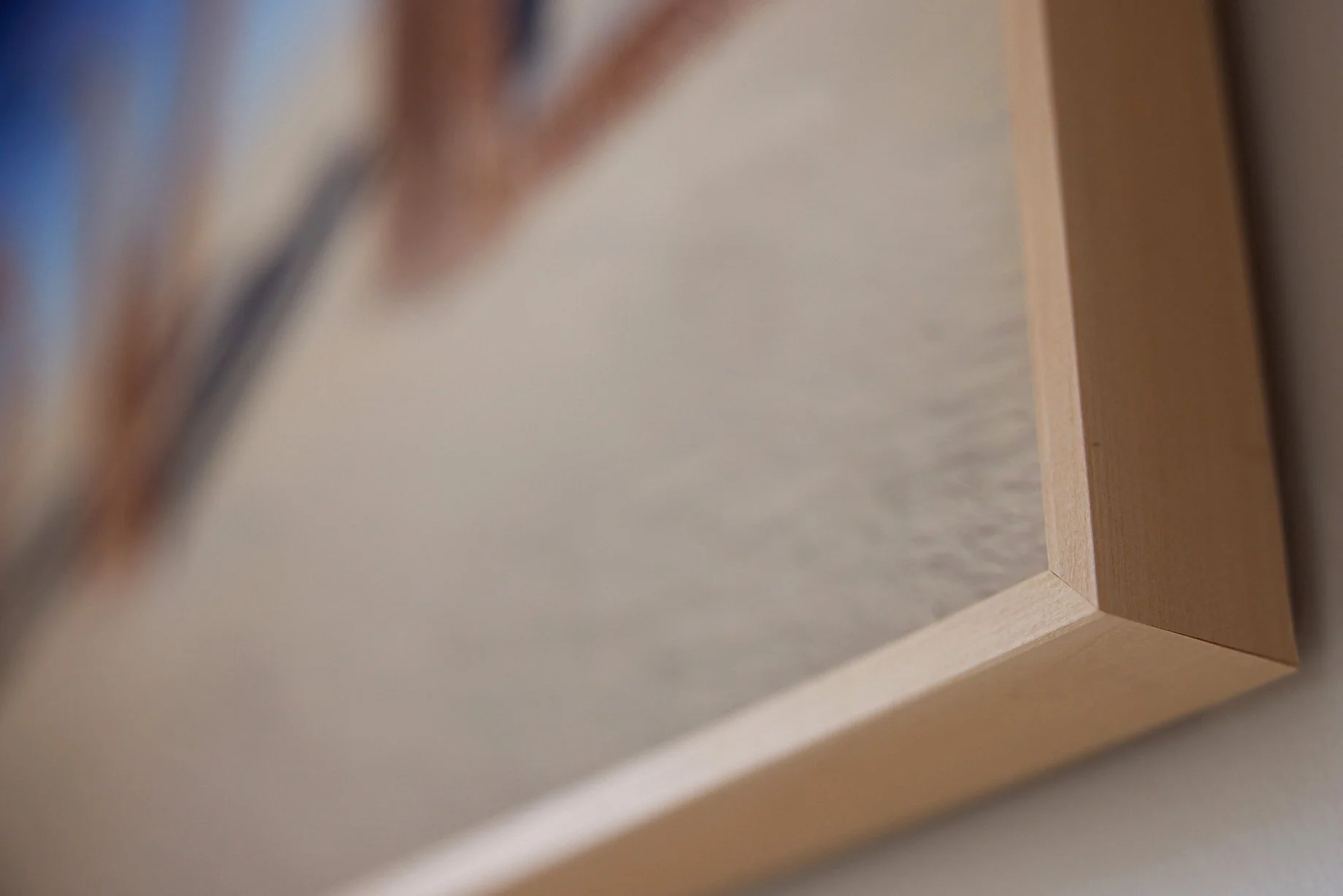 Vue partielle d'un meuble en bois clair, prise de biais, avec un mur blanc en arrière-plan.
