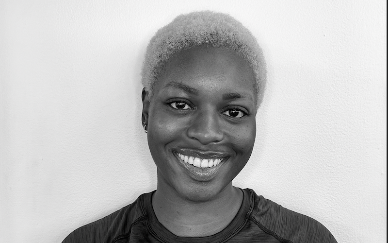 Black and white photo of a woman with short, curly, light-colored hair smiling at the camera.