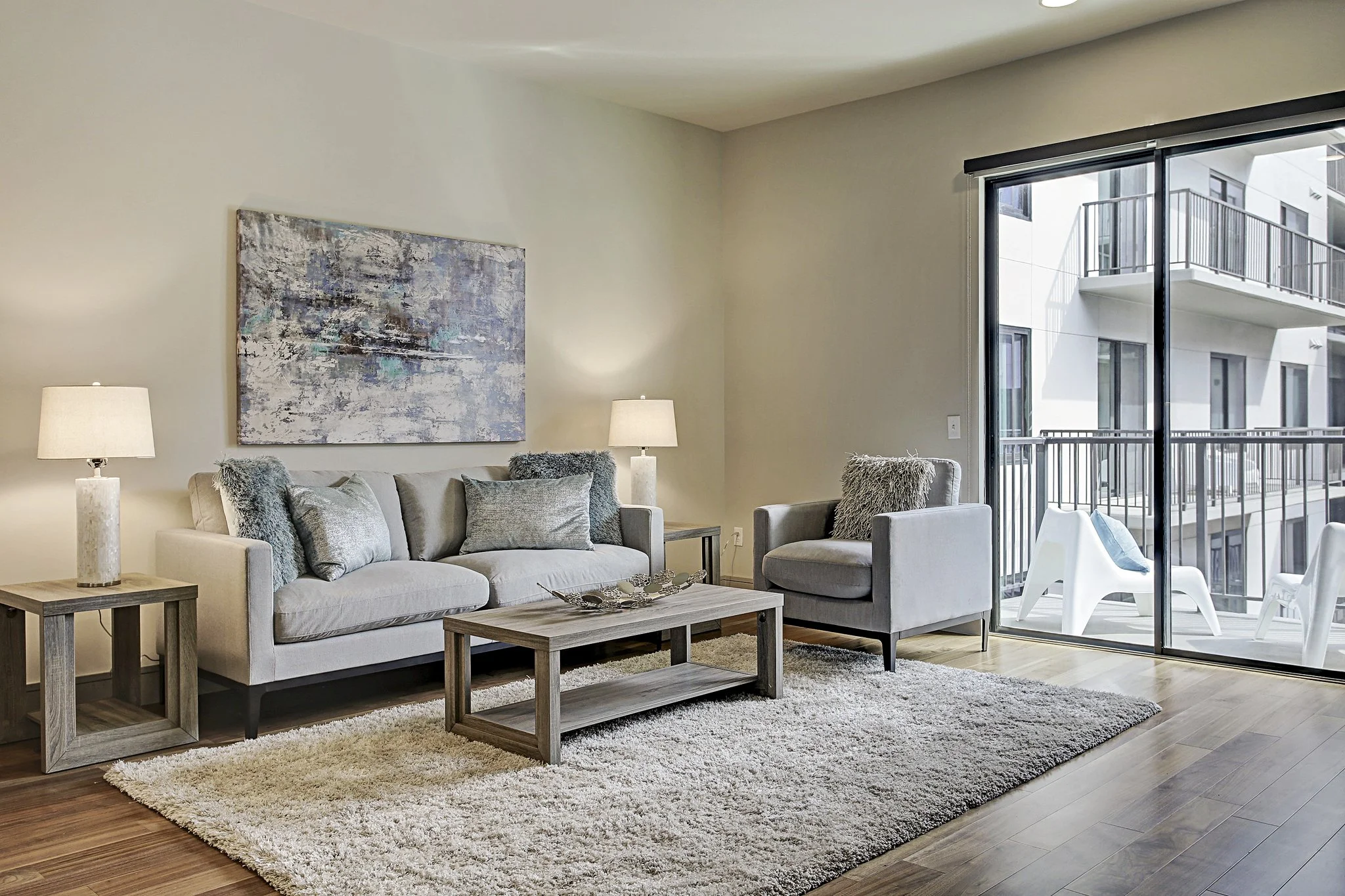 Fully furnished corporate apartment living room in Houston, Texas, featuring comfortable seating, modern décor and a private balcony.