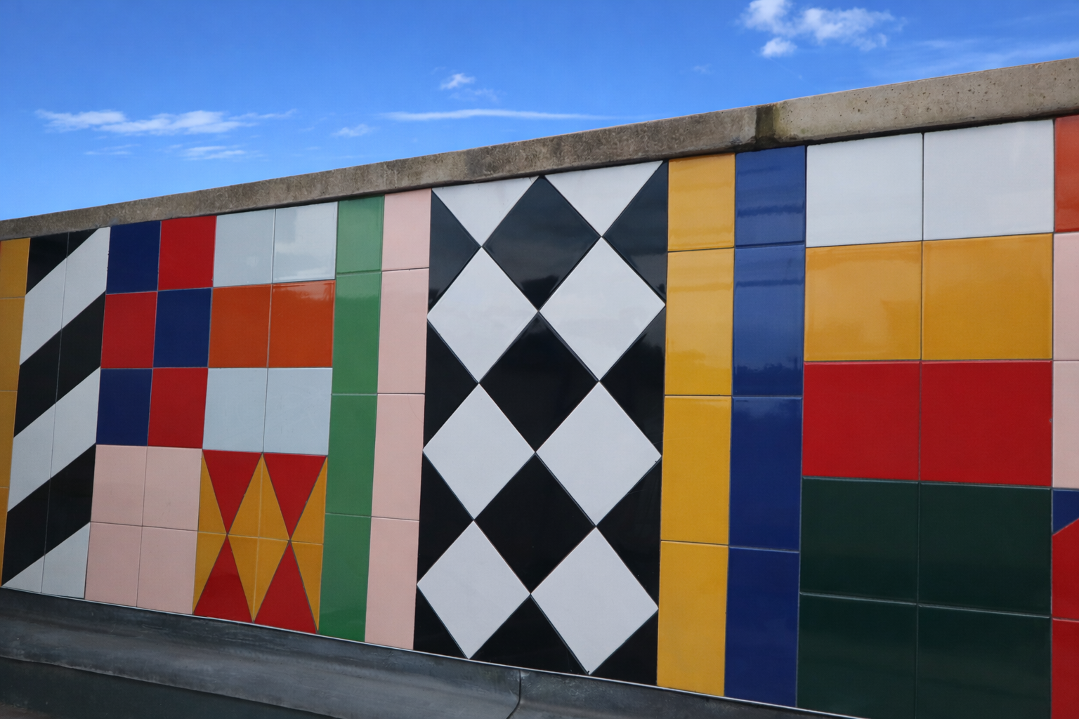 Colourful tiled wall under blue sky.png