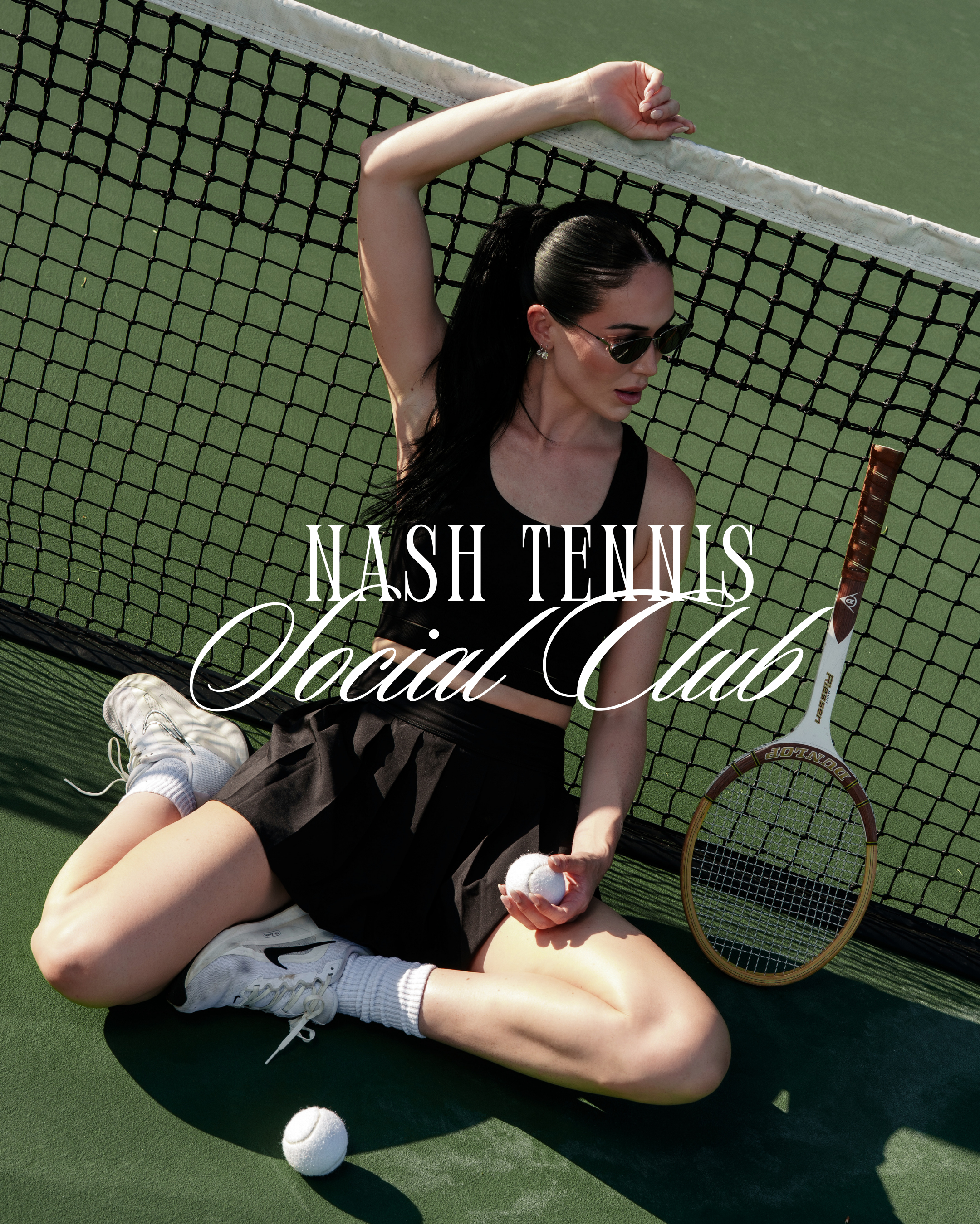 A woman with long black hair, wearing sunglasses, a black sleeveless top, black shorts, and white sneakers, is sitting on a green tennis court. She is leaning against the net with her left arm raised above her head, holding a tennis ball in her right hand, with a tennis racket placed it on the ground beside her. The text overlay says "Nash Tennis Official Club."