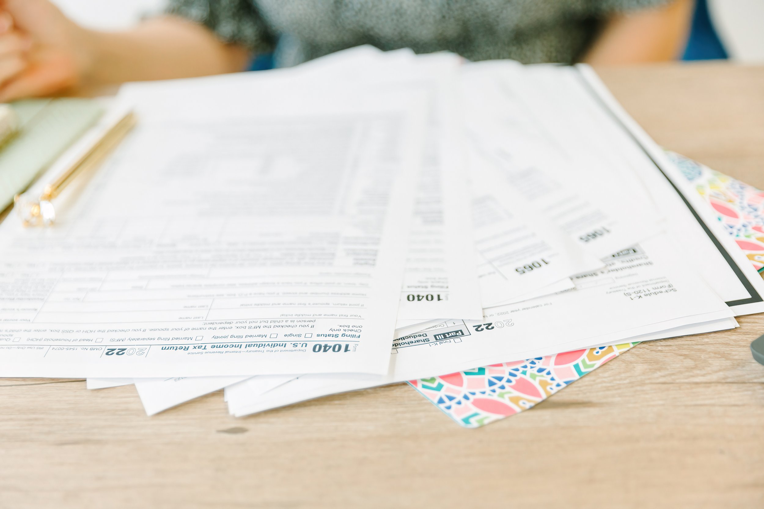 A stack of paper documents with a multicolored decorative border at the bottom, placed on a wooden surface.