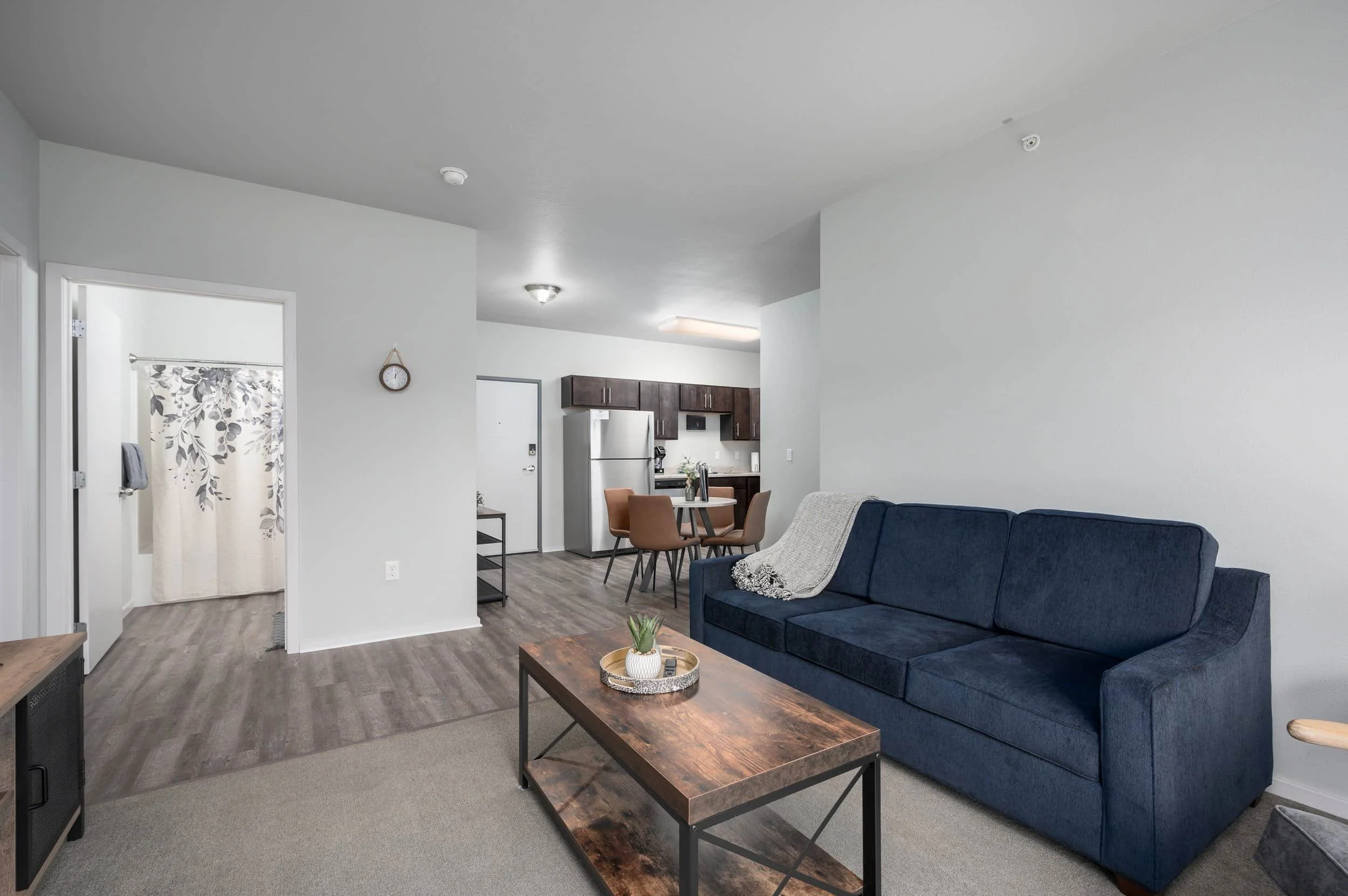 Modern living room with a blue sofa, wood coffee table, and open kitchen—perfect for apartments in Rochester.