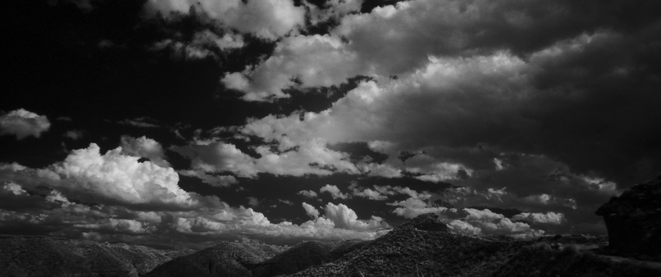 Un paesaggio montano con un cielo nuvoloso.
