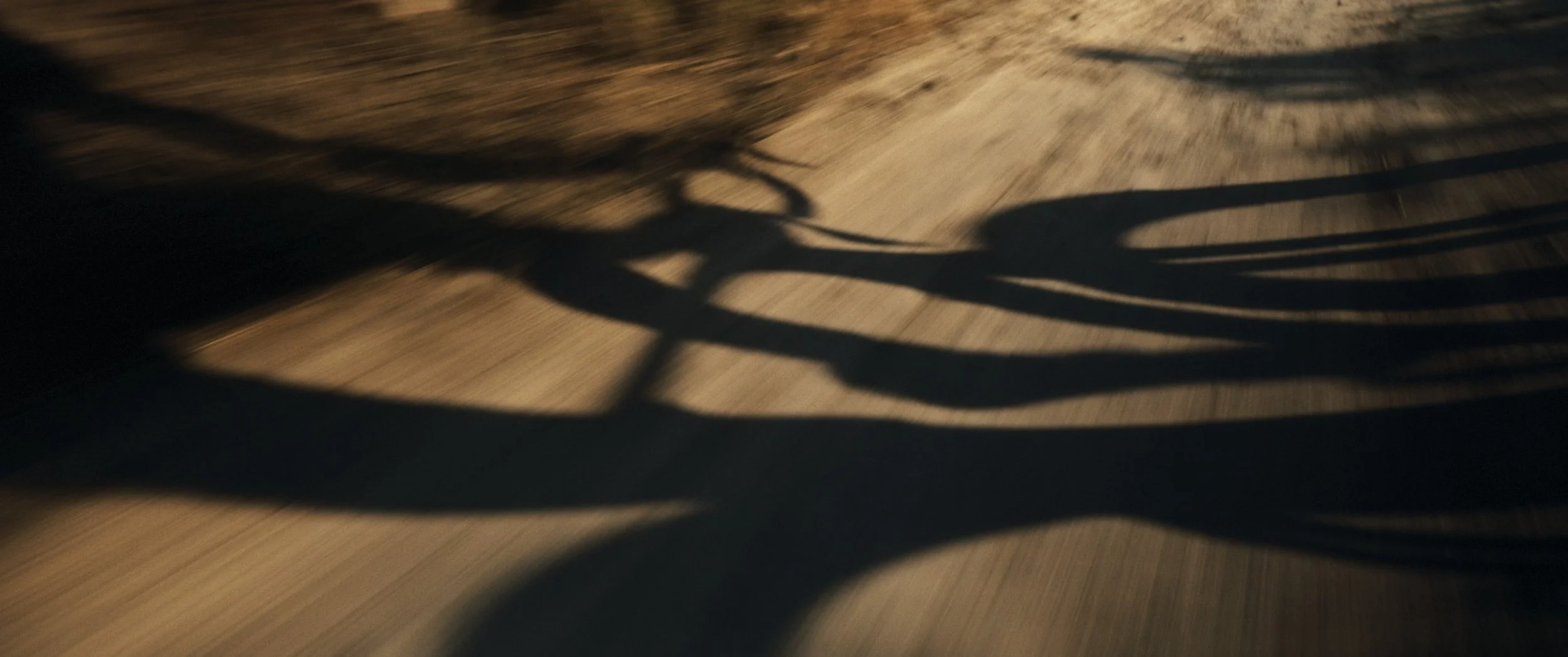 Ombra di una bicicletta sulla strada di terra al tramonto.