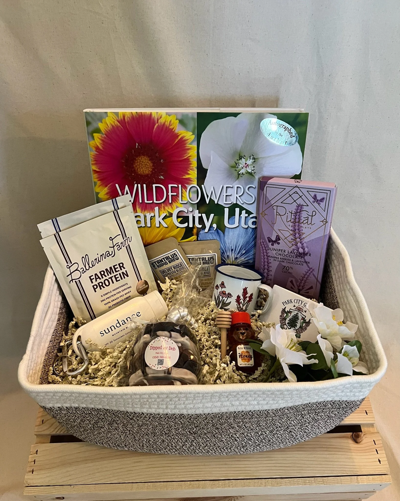 Park City gift basket with wildflower book, floral mug, chocolate, honey, coffee, pretzels, and sunscreen