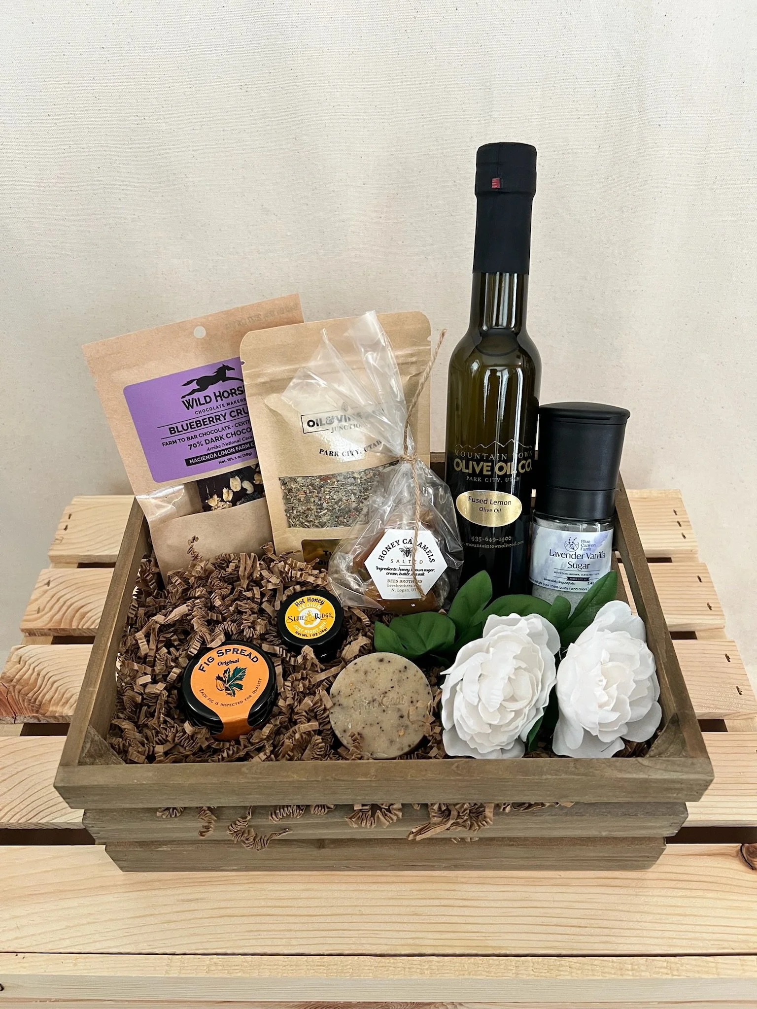 Utah artisan food gift basket with olive oil, honey, chocolate, caramels, and fig spread in wood crate