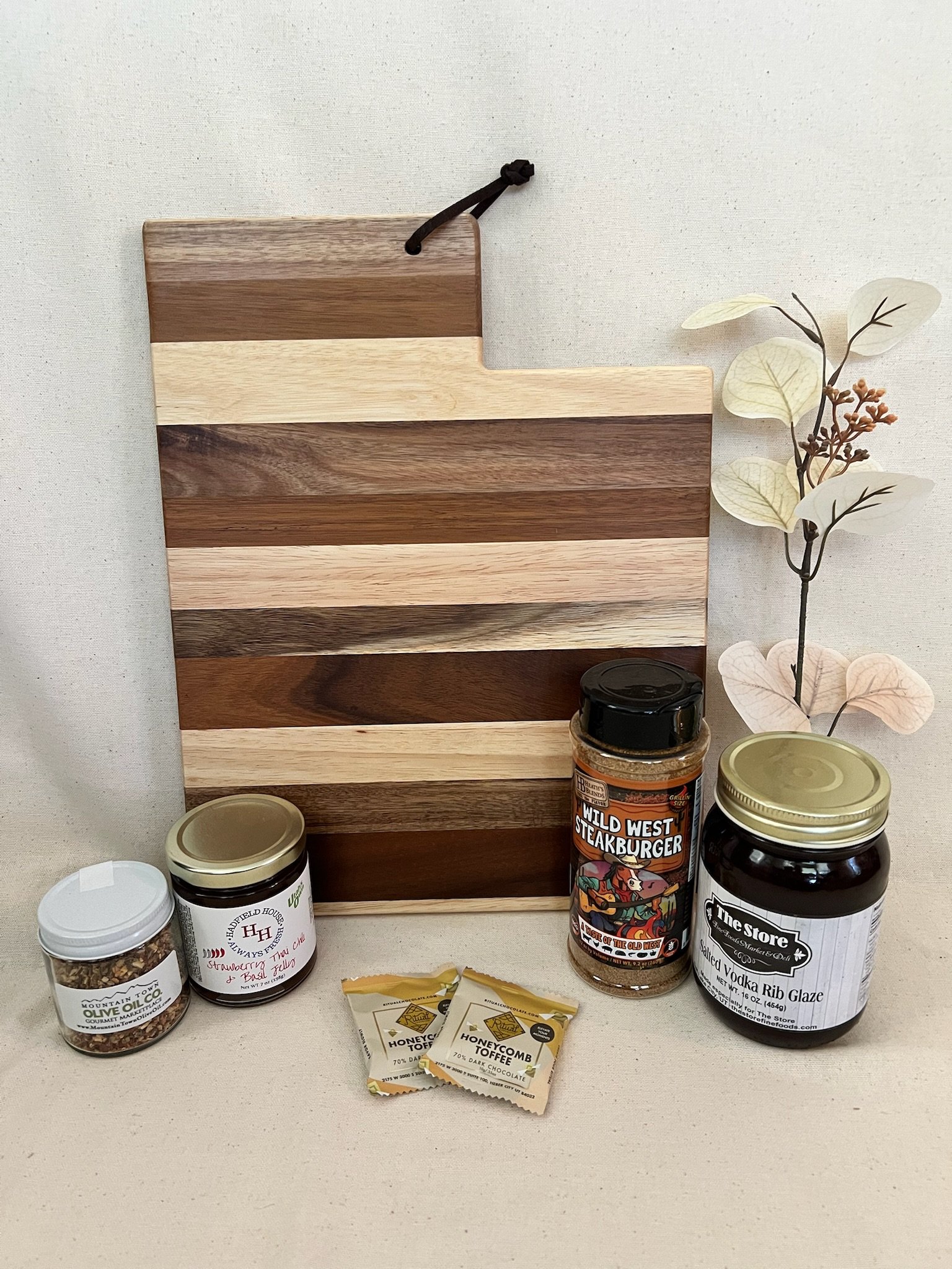 Utah BBQ gift basket with steak seasoning, rib glaze, jelly, olive oil blend, and chocolate on a Utah-shaped cutting board