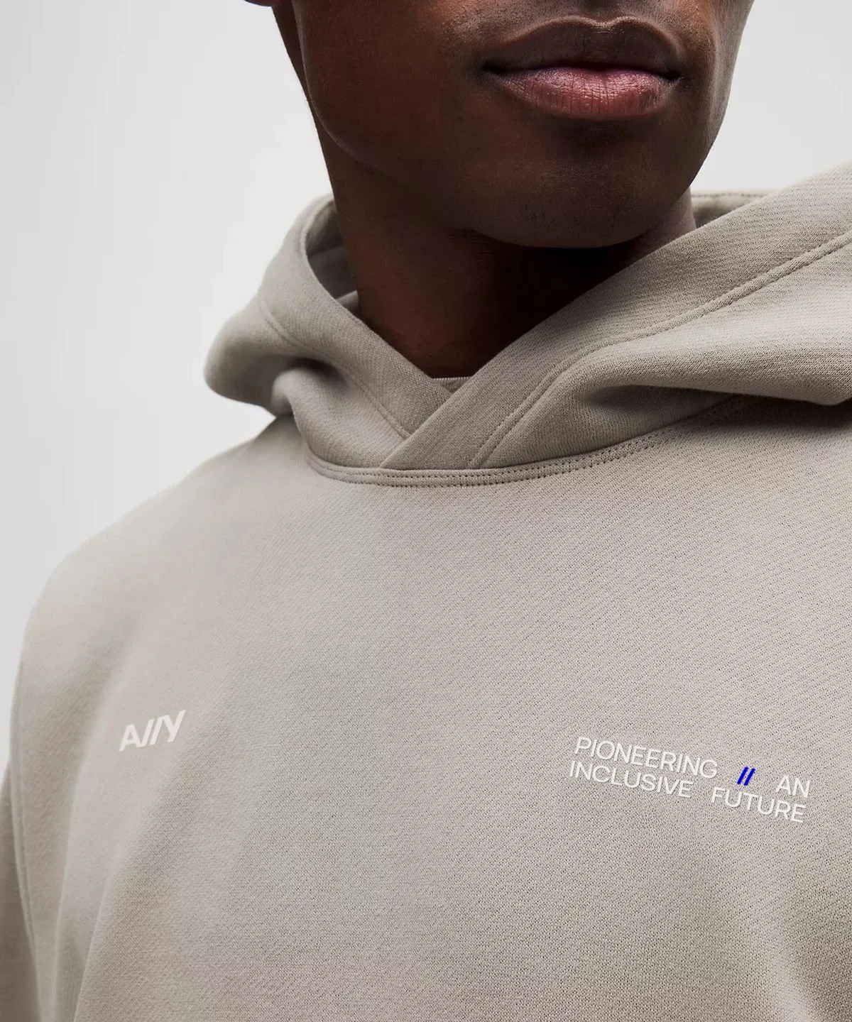 Close-up of a person wearing a beige hoodie with the words 'PIONEERING INCLUSIVE FUTURE' printed on the chest.