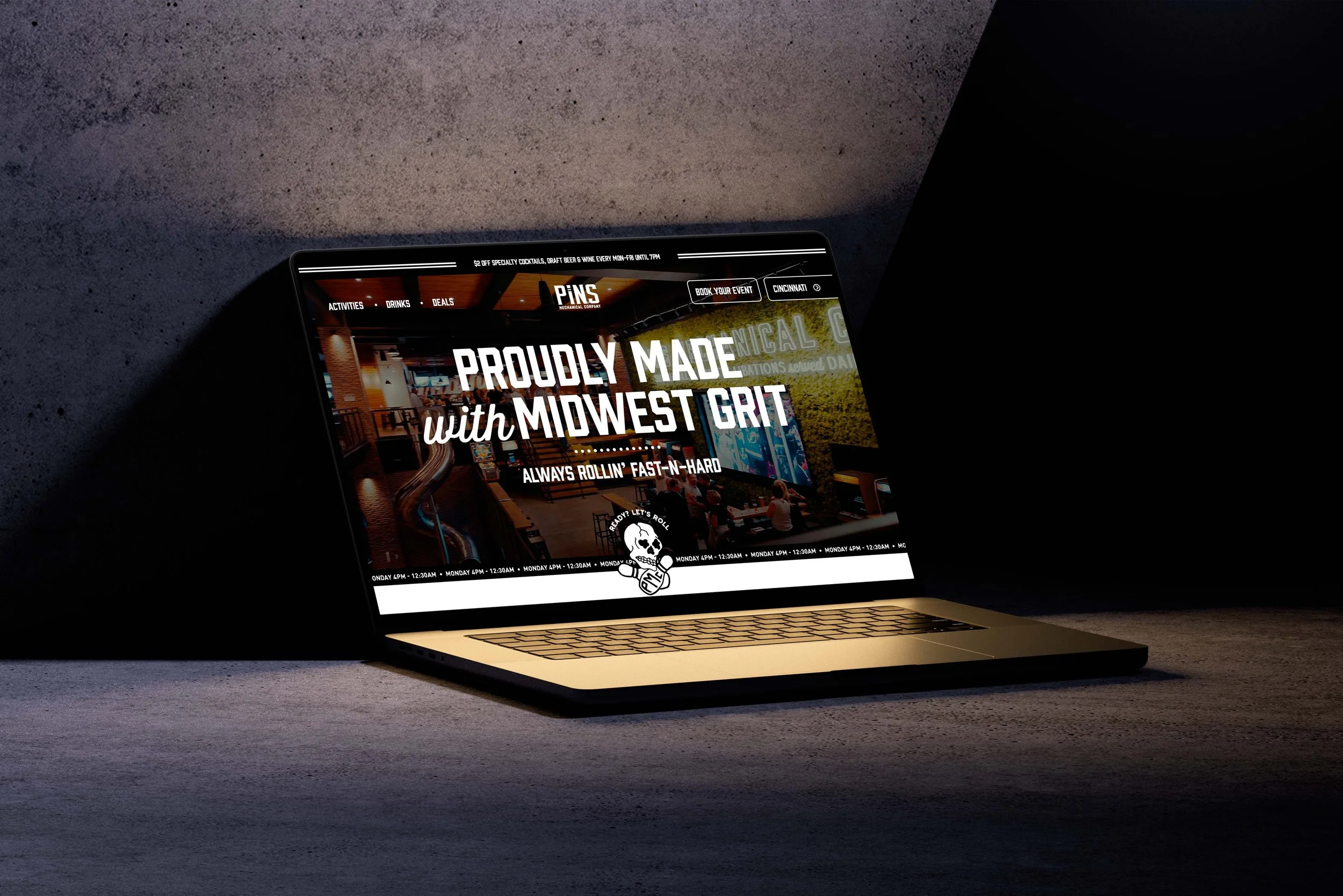 Laptop on a dark surface displaying a website for Pins Mechanical, a location in Cincinnati, with text promoting Midwest grit and a roller-skating theme.