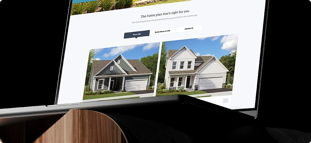 Laptop screen displaying a home design website with images of two different house models.