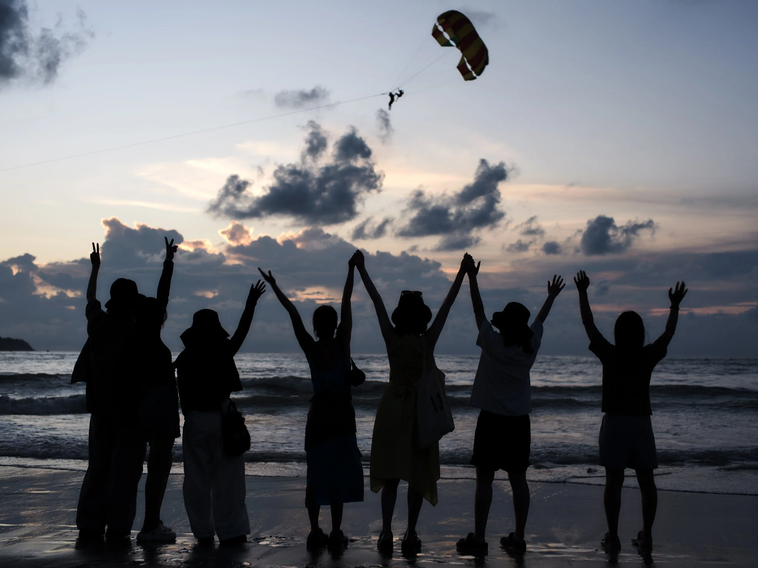 Friends watch the sunset on a Thai beach.