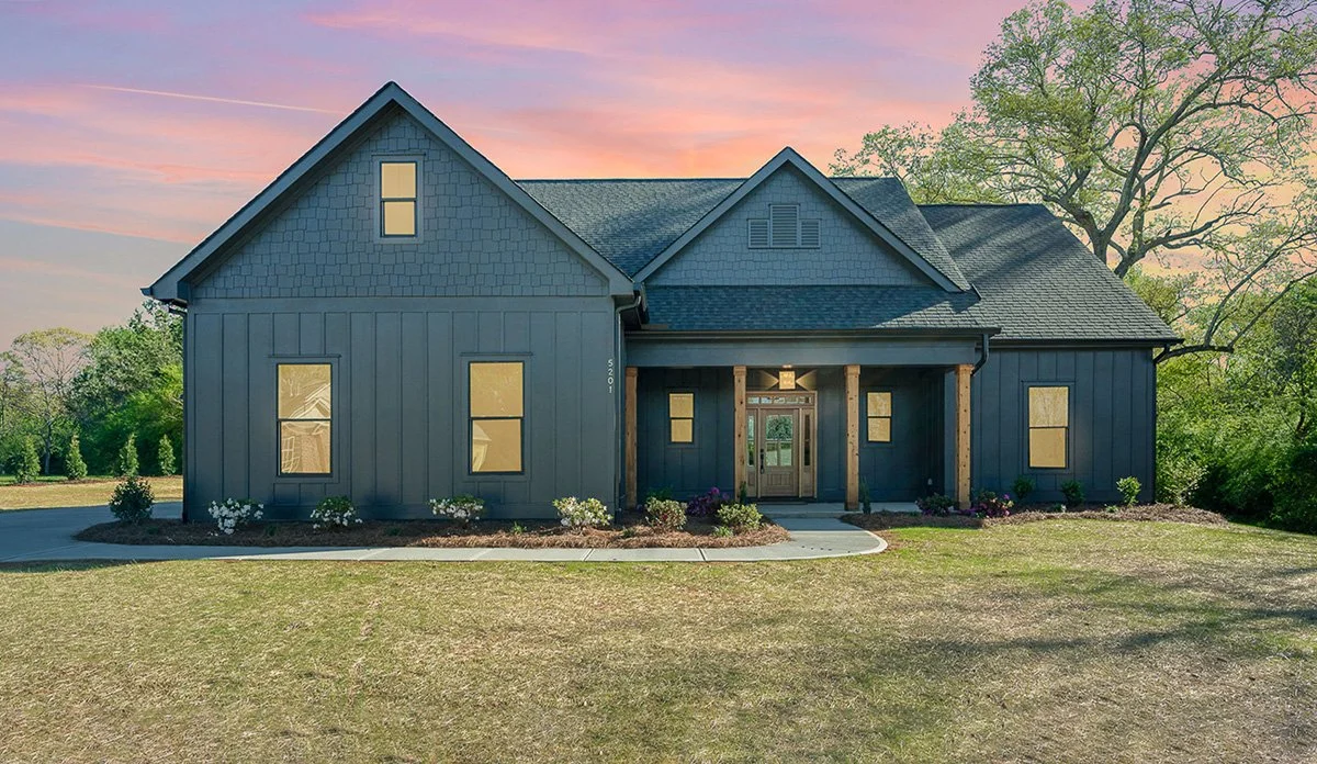 Modern farmhouse with black exterior, natural wood accents and neatly landscaped lawn