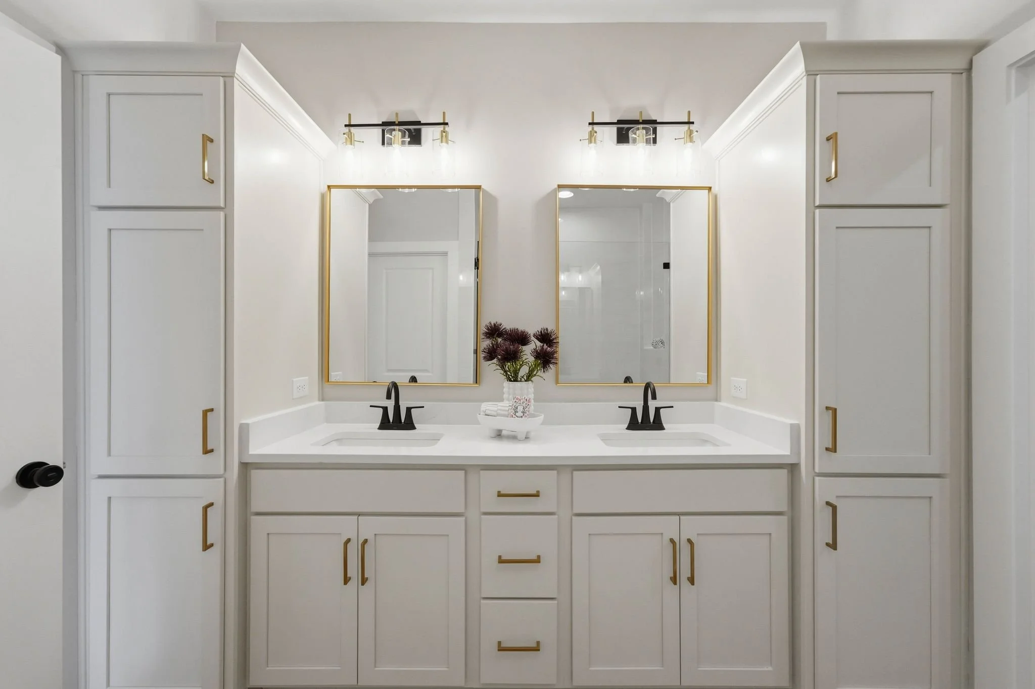 Luxury primary bathroom with white cabinetry with gold and black accents