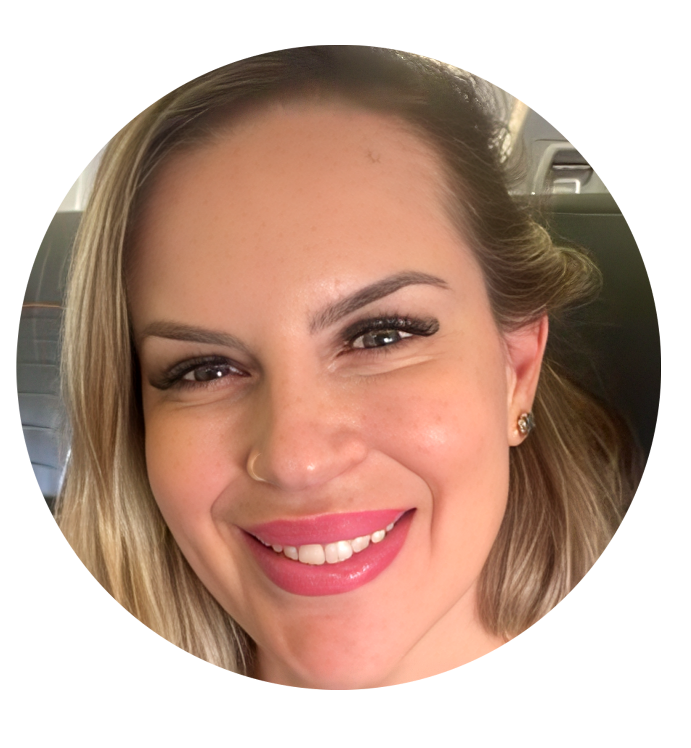 Primer plano de una mujer sonriendo, con cabello rubio, ojos marrones, usando maquillaje y pendientes de oro.