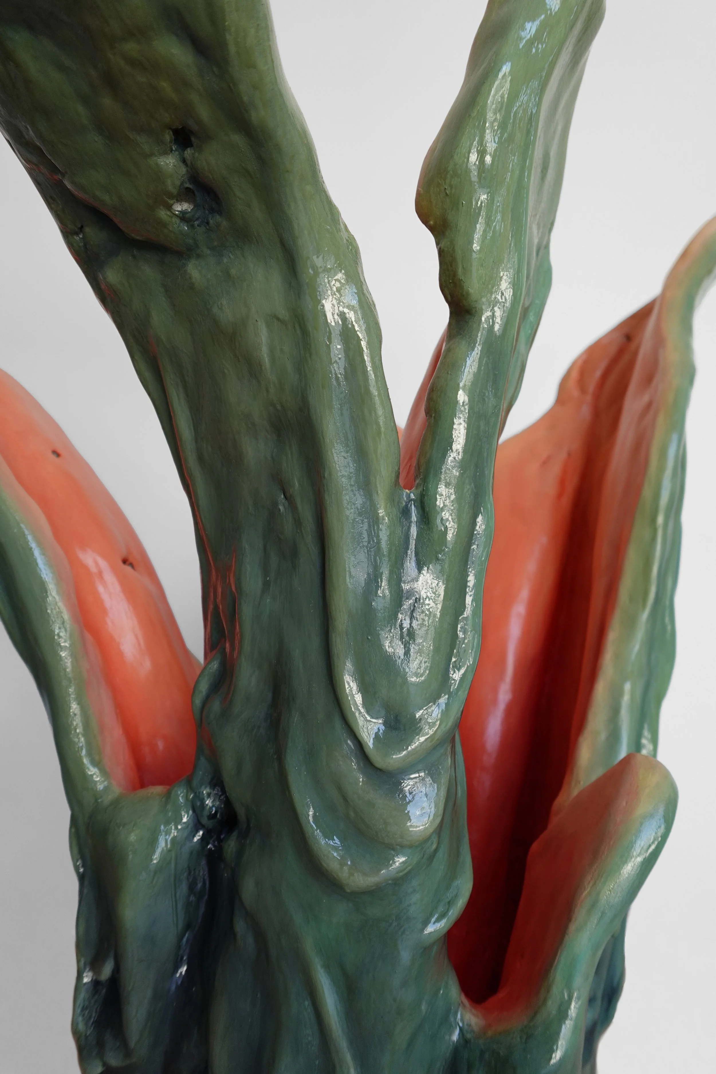 Close-up of a ceramic art piece resembling a cactus with textured green and orange surfaces.