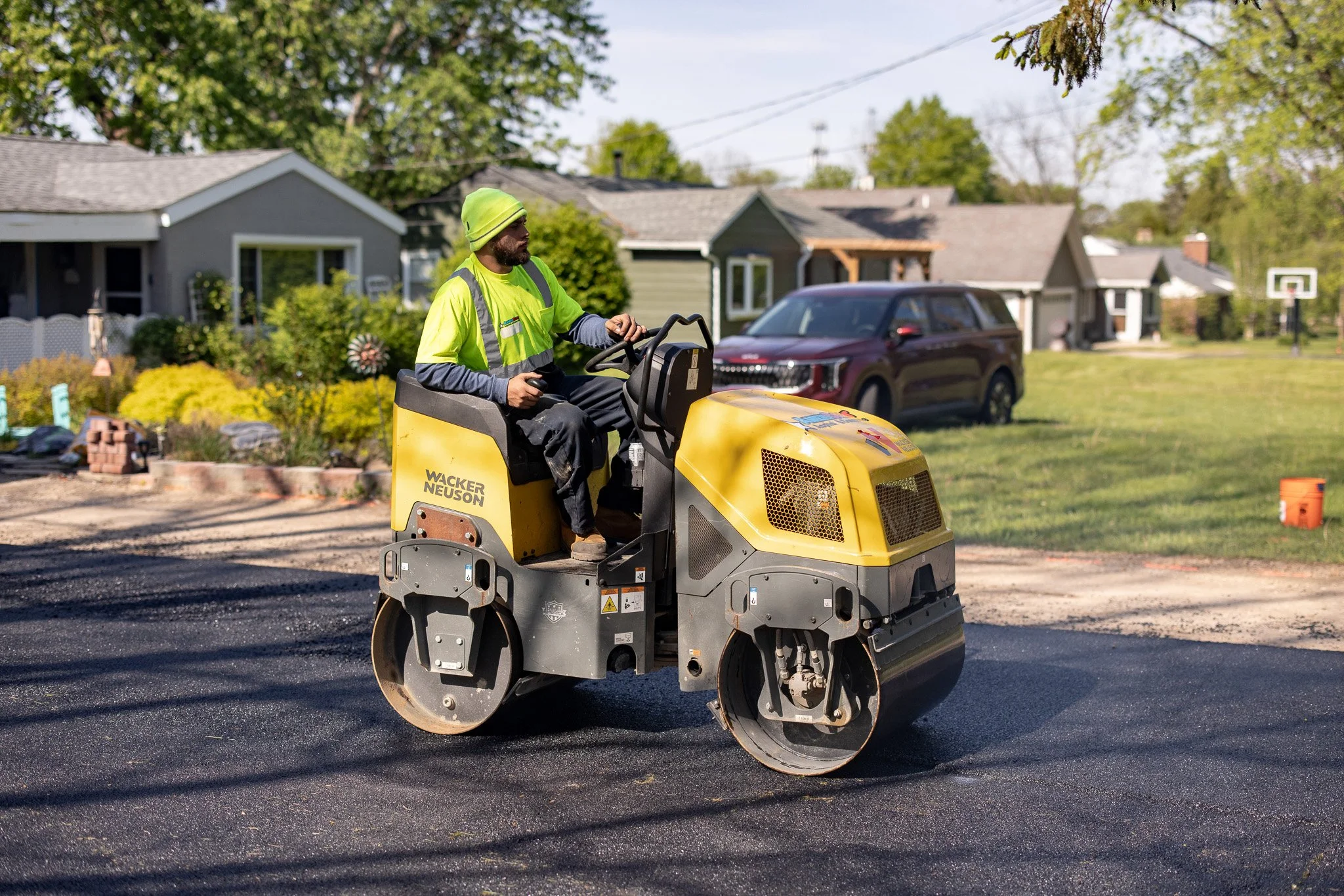 Americoat asphalt crew operating a Wacker Neuson roller compactor during a residential driveway paving job — commercial photography by Signature Narratives, Ohio