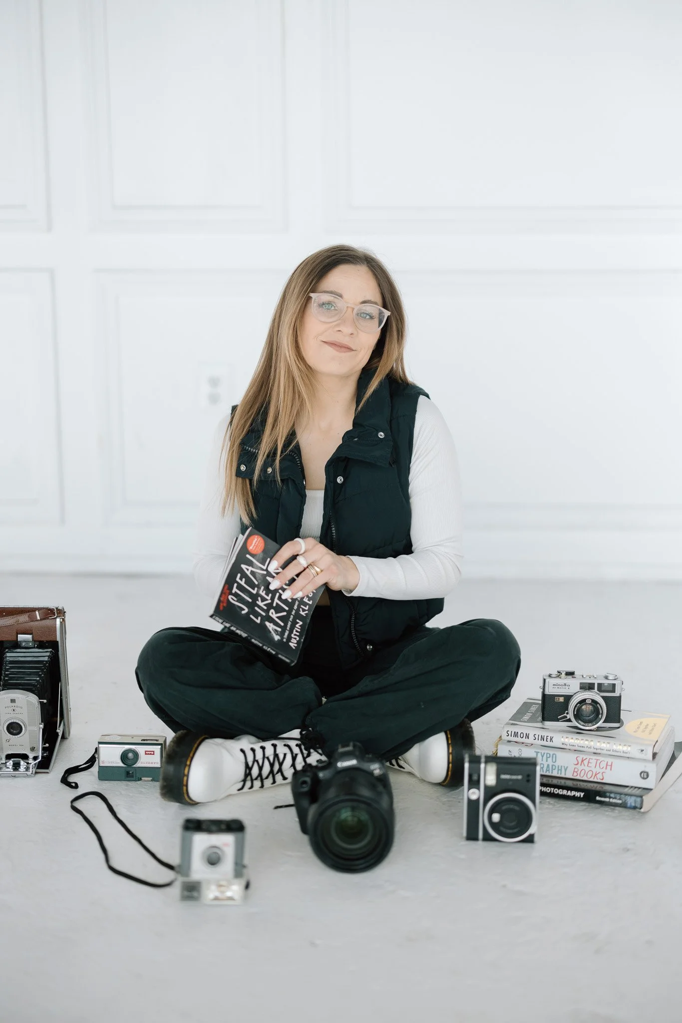 Brand portrait of Polly Sellers surrounded by vintage cameras and photography books in a bright studio — brand photography by Signature Narratives, Ohio