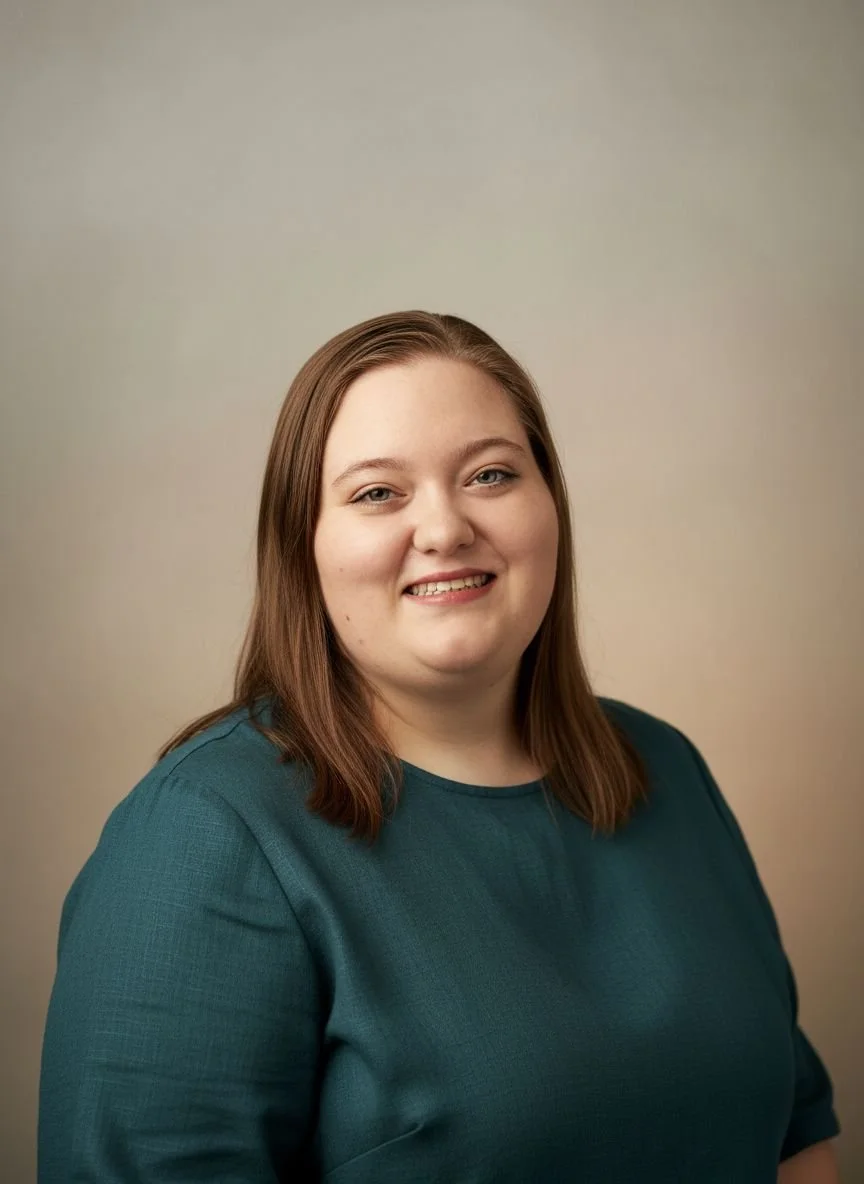Sam with shoulder-length brown hair, wearing a teal top, smiling against a neutral background.