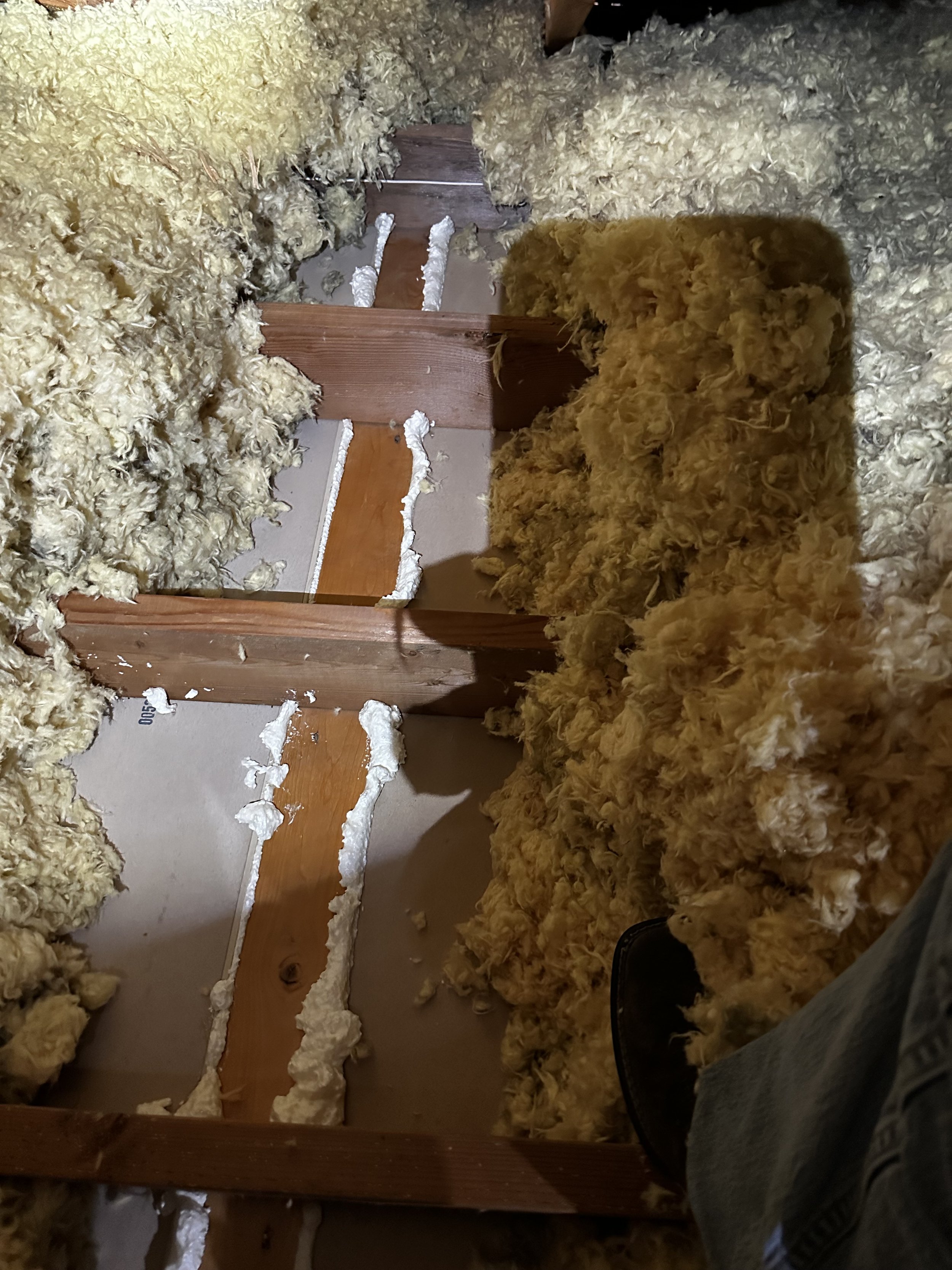 Insulation material between wooden floor joists in a building under construction or renovation.