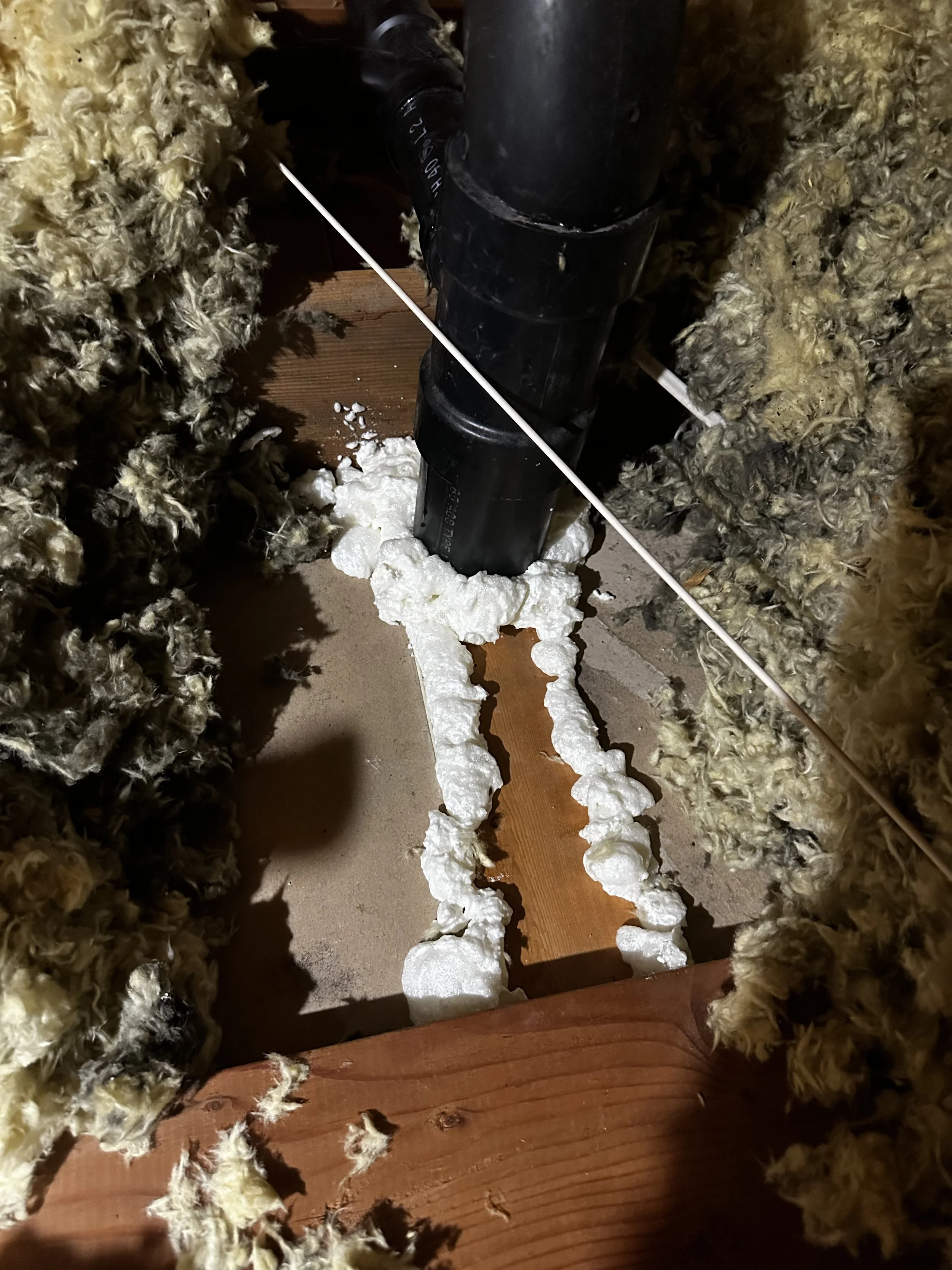 Inspecting or repairing a plumbing pipe inside the wall, surrounded by insulation foam.