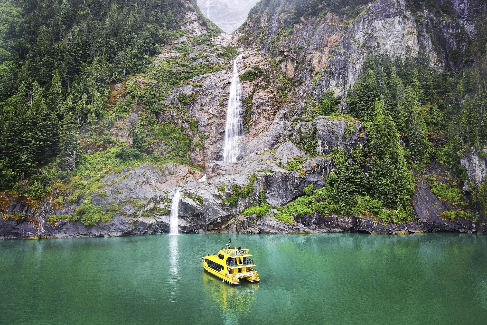 Catamaran with scenic waterfall in the background