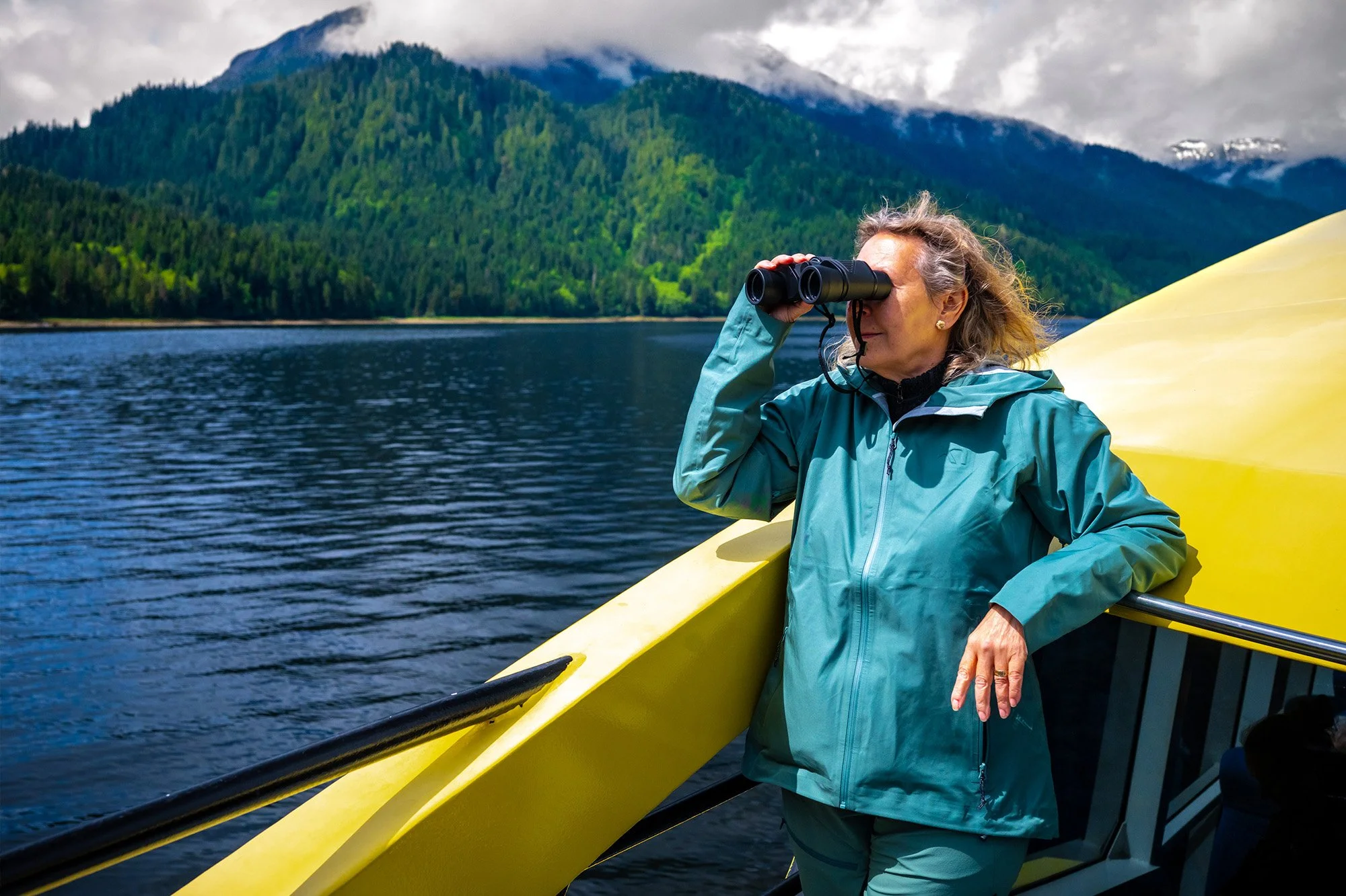 Tour goer on catamaran looking through binoculars