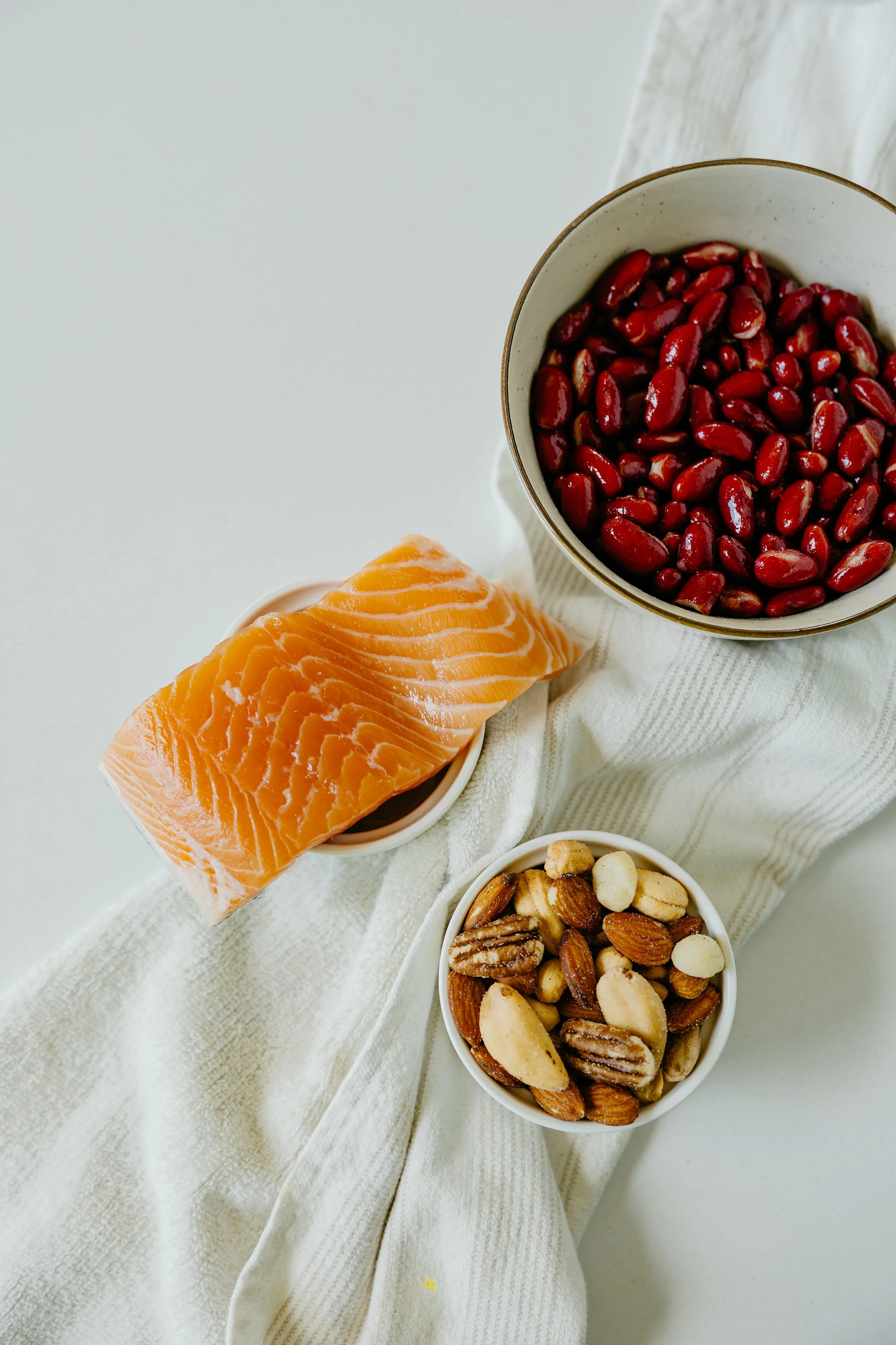 Saumon, noix du Brésil et légumineuses illustrant une alimentation adaptée à la ménopause et à la santé hormonale