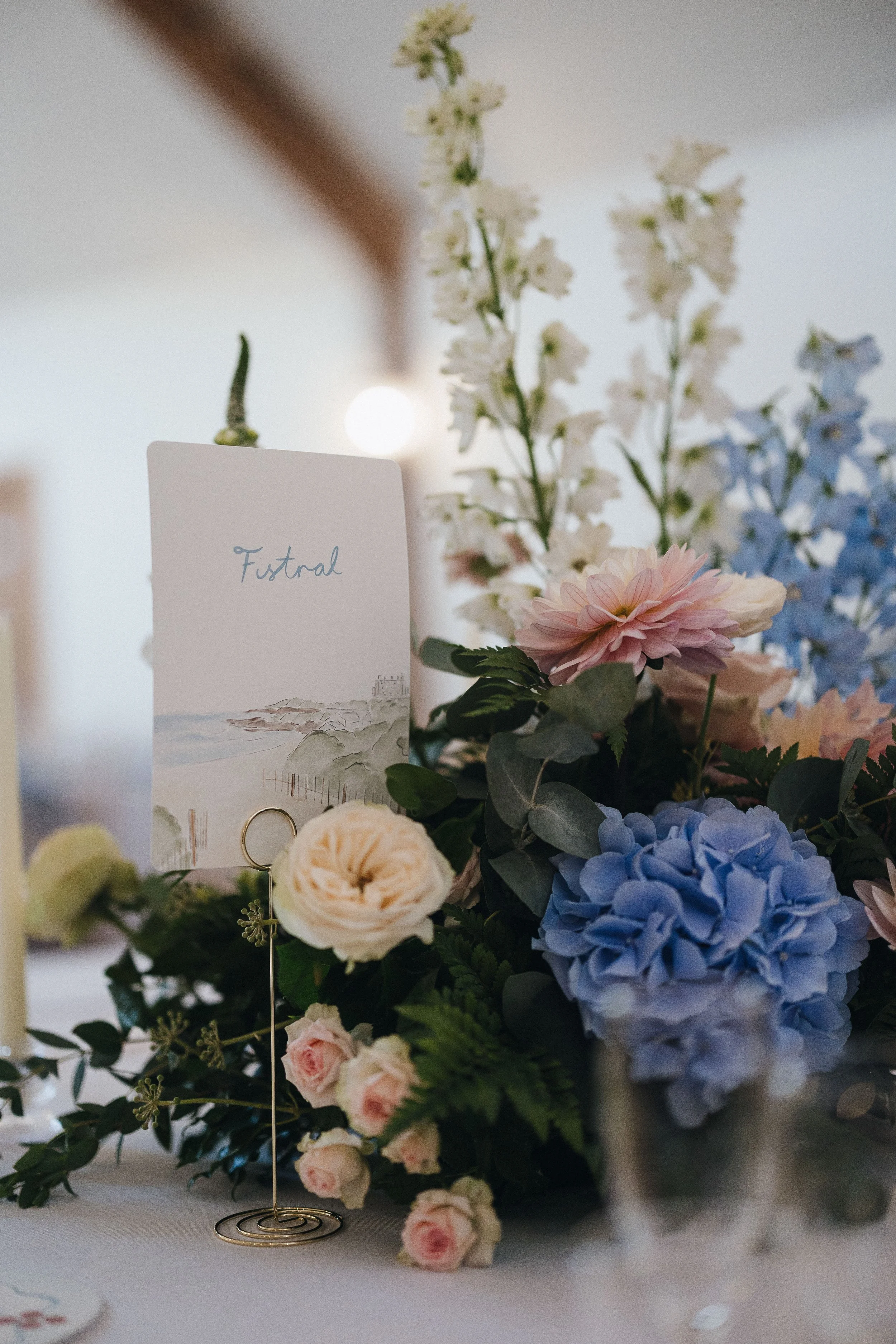 A bespoke illustrated table name featuring a hand drawn beach for each table and hand written names at Launcells Barton