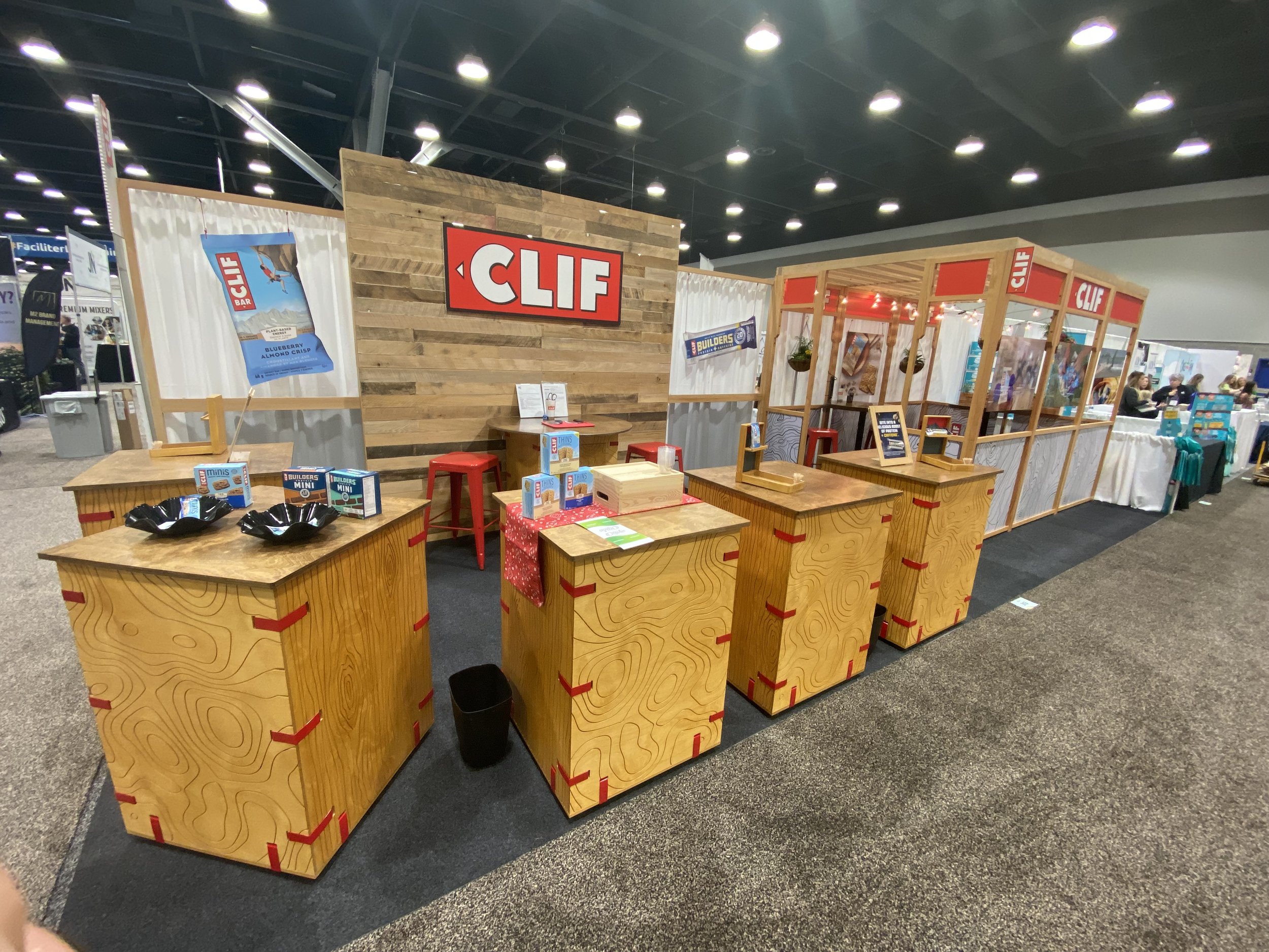 Clif at CHFA West 2023 Modular 'Snap Cab' cabinets with custom topo engraving. Lightweight reclaimed wood wall looking as nice on it's 17th set up (last at CHFA) as its first use. Modular 'Cafe' in background, adapted to the smaller 10x30 space, wit