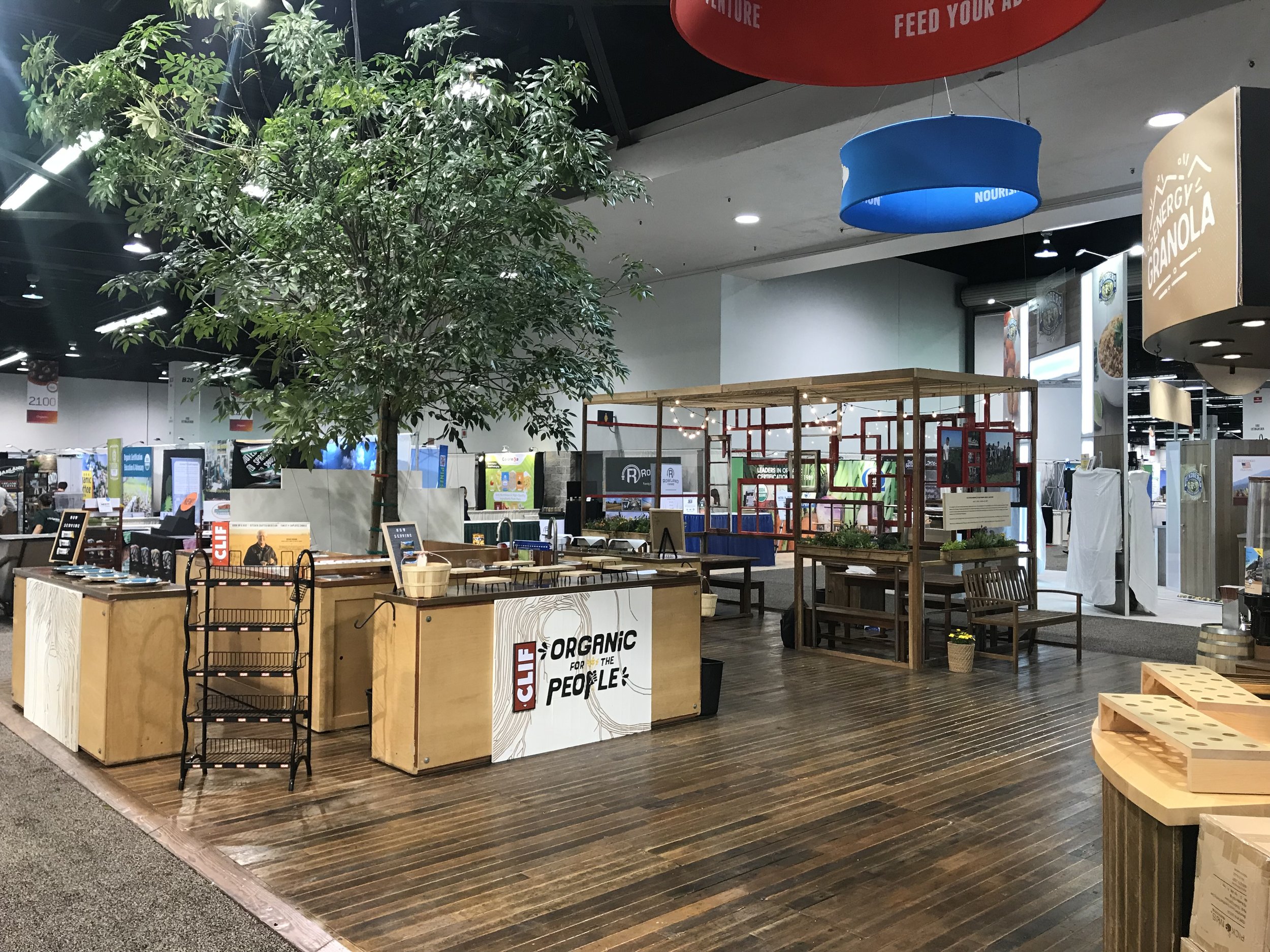 Clif booth at NPEW with live tree and root design counter fronts with hand painted lettering