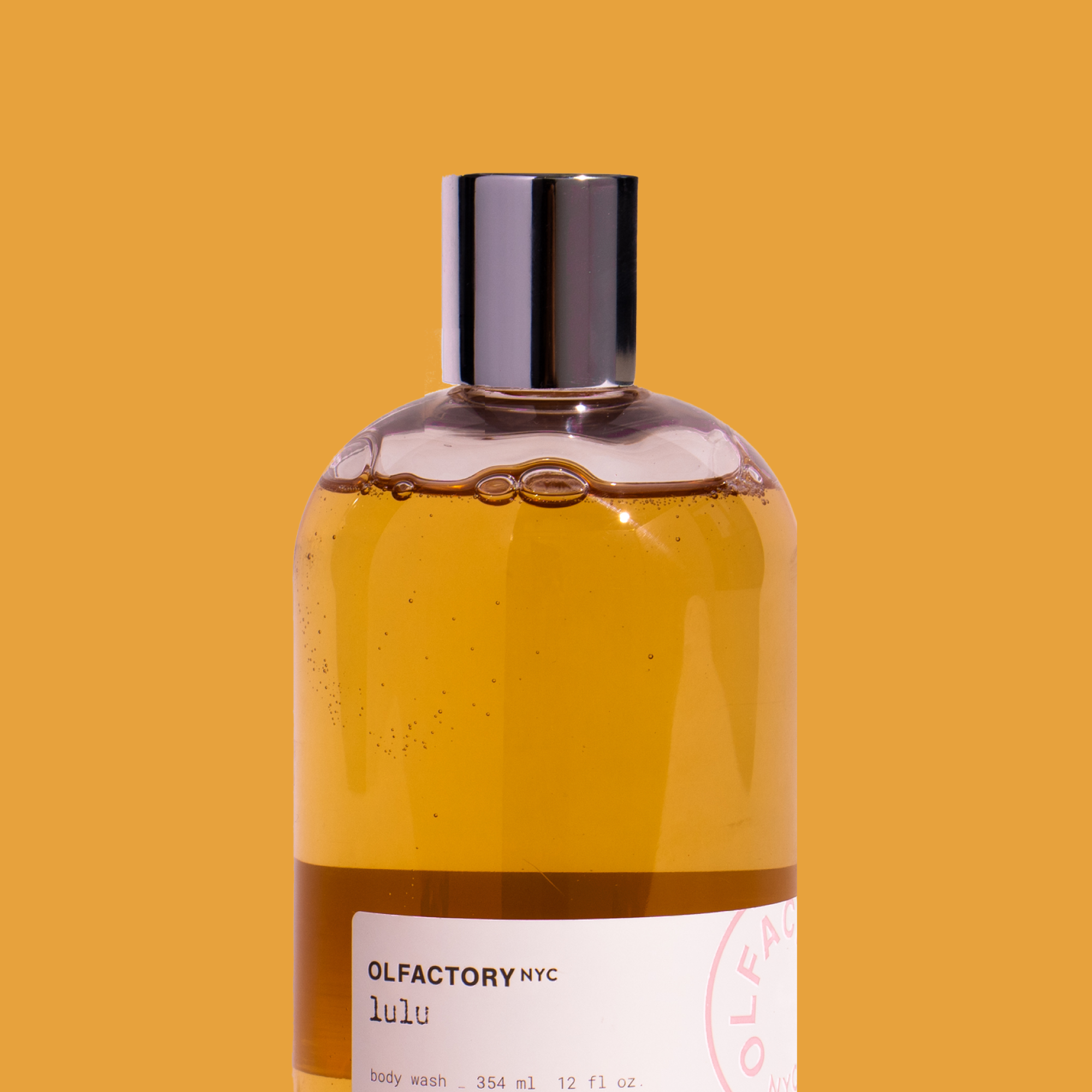 Bottle of Olfactory NYC Lulu body wash on orange background