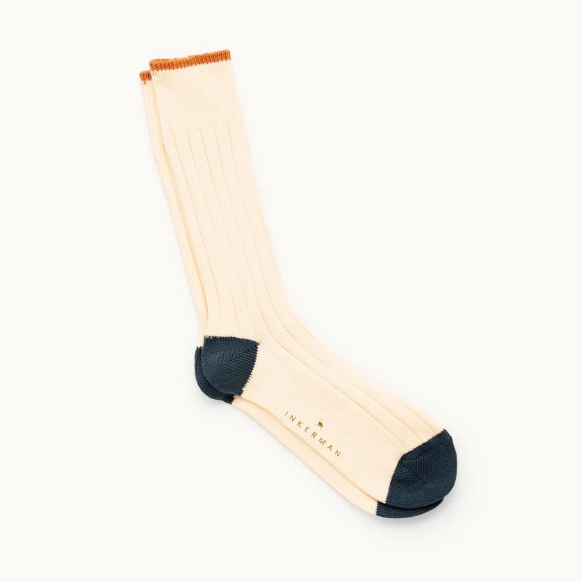 Cream sock with dark toe and heel, orange cuff, and "Inkerman" logo.