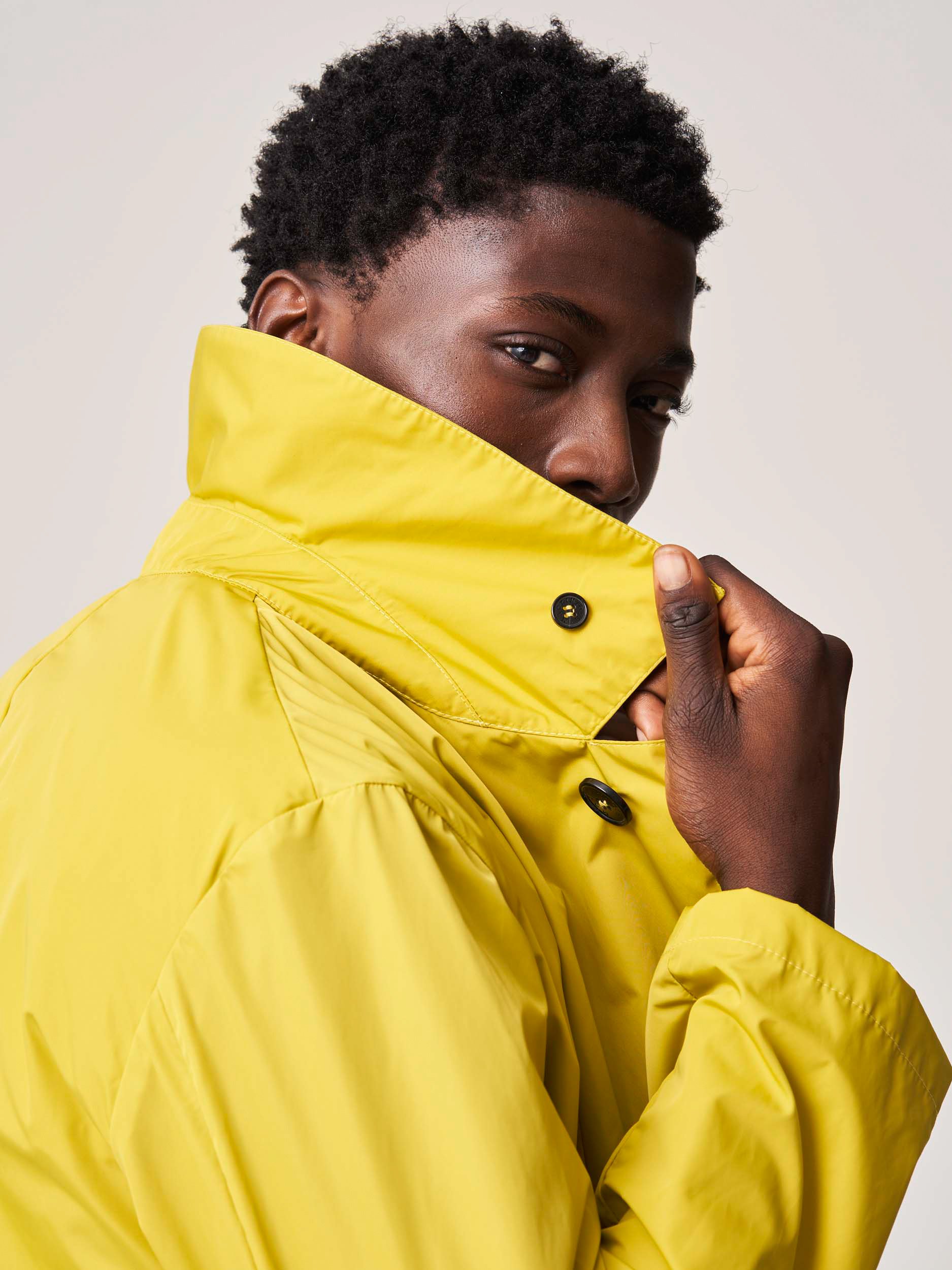 Person wearing a yellow jacket with collar raised.