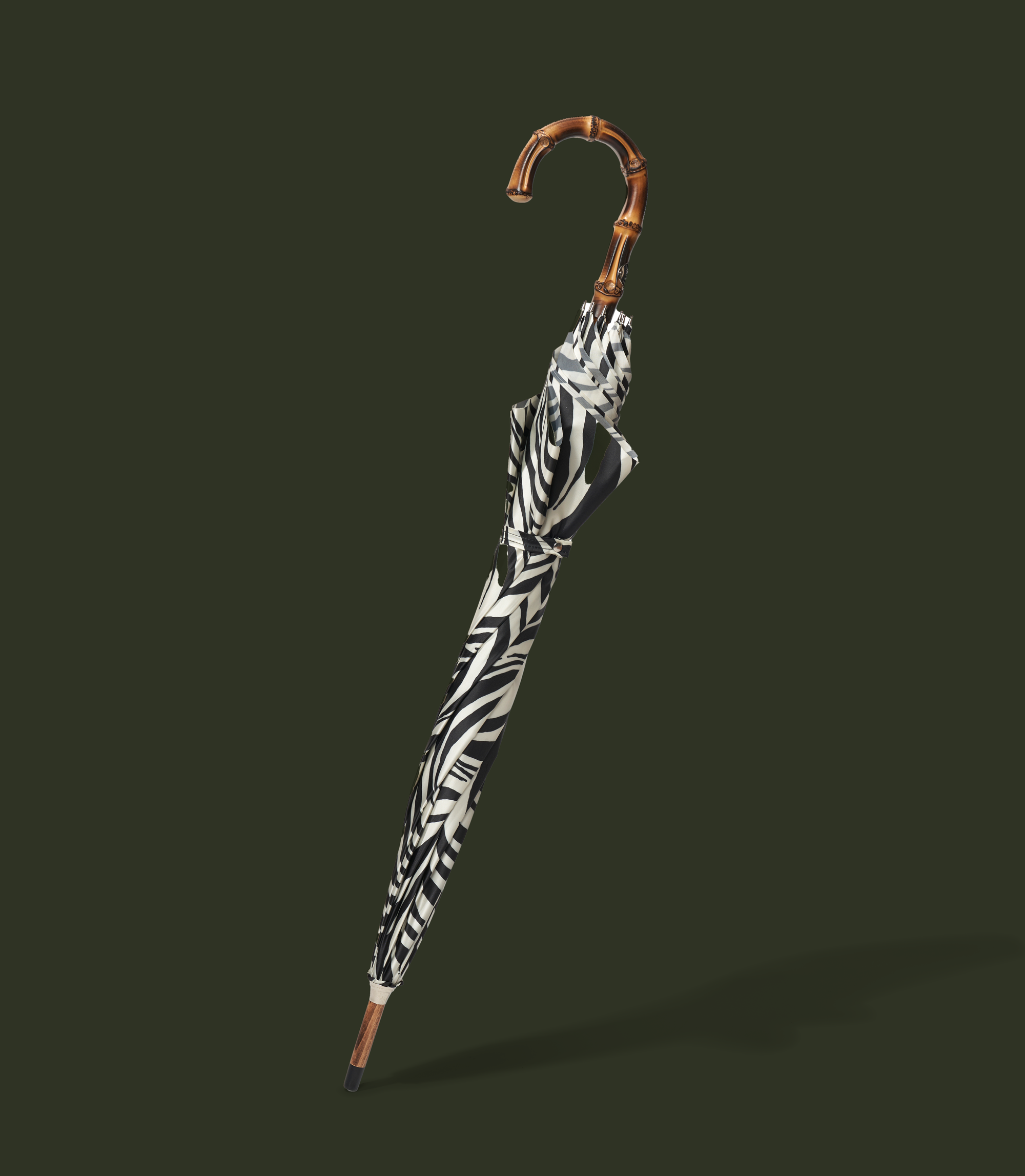 Striped umbrella with a curved wooden handle on a dark green background.
