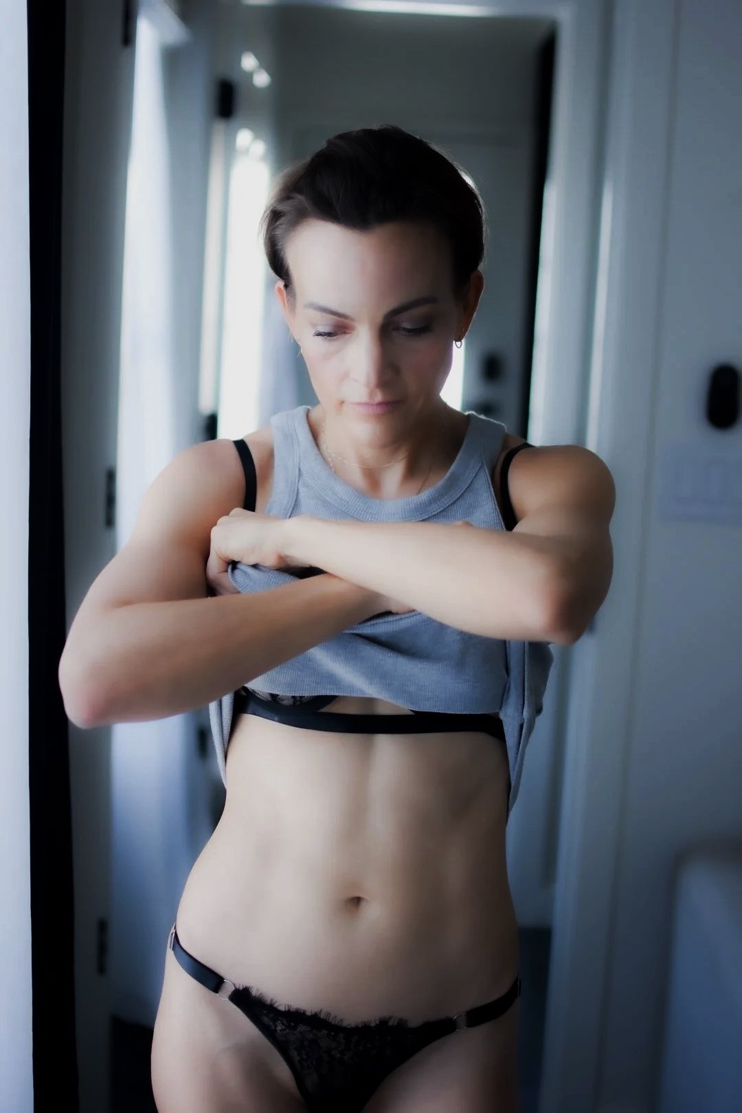 Woman lifting tank top to reveal lingerie