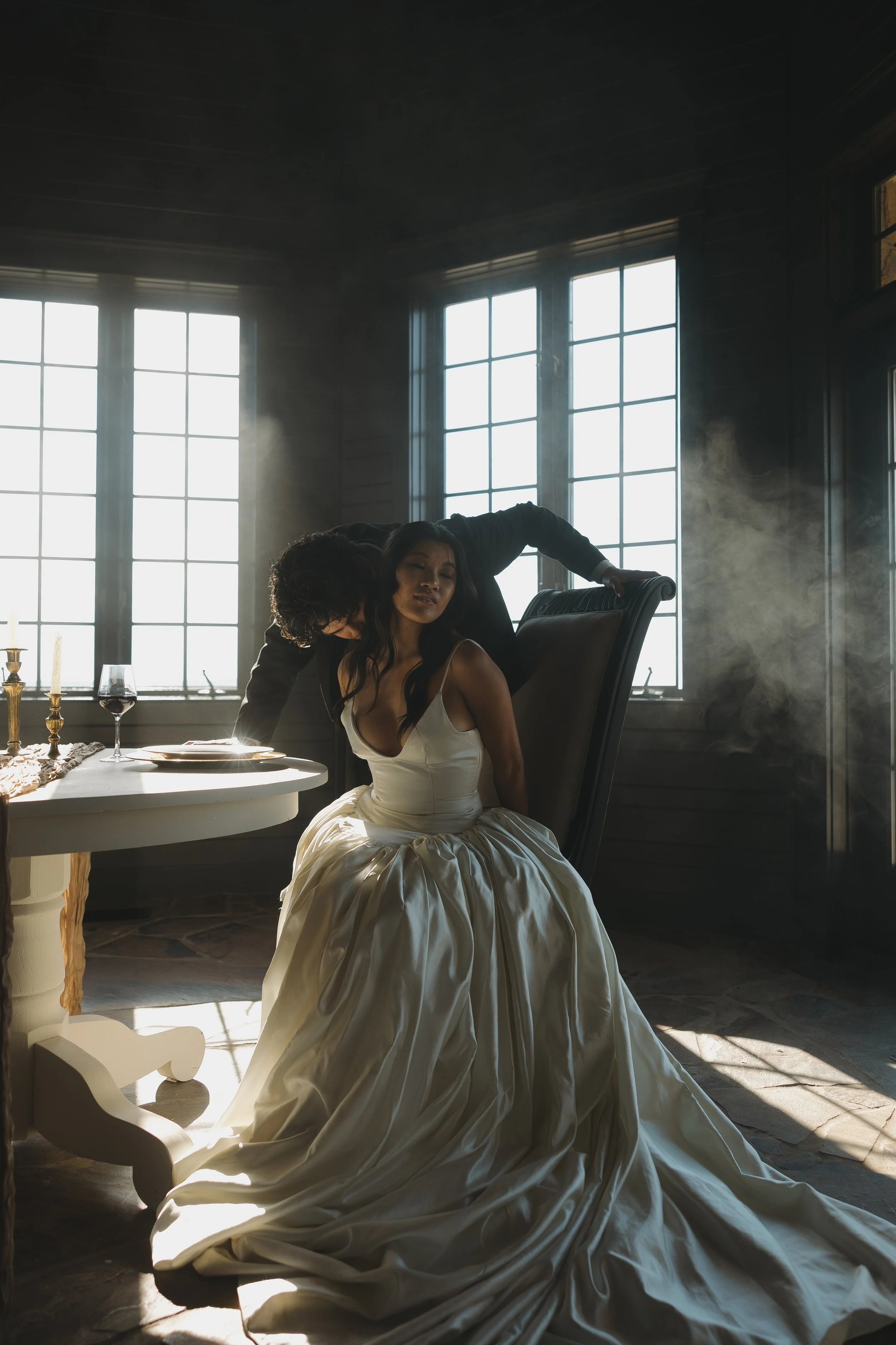 A bride and groom close-up under a clear umbrella during their wedding, sharing an intimate moment with the bride holding a bouquet of white flowers.