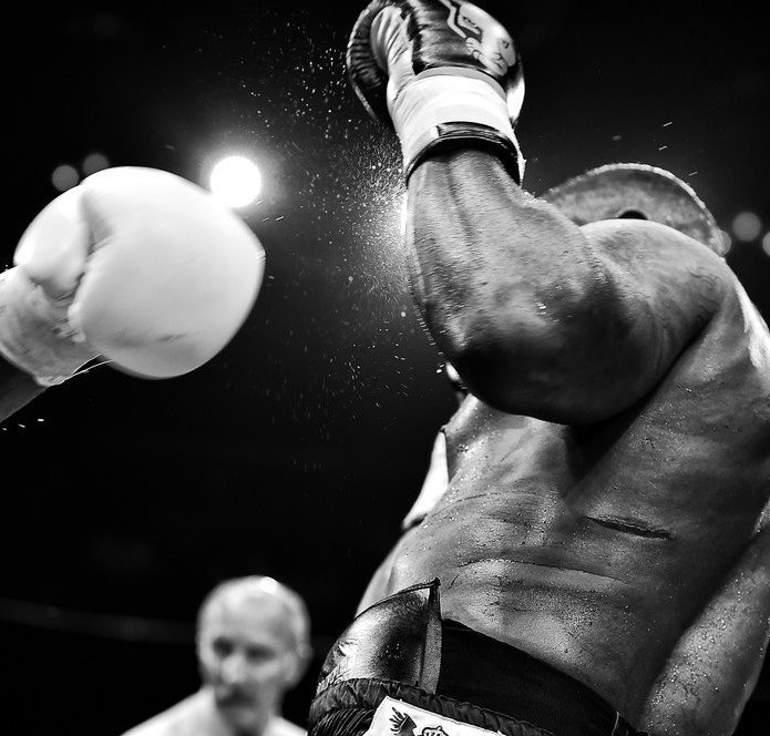 Black and white photo of two boxers in action, one delivering a punch.
