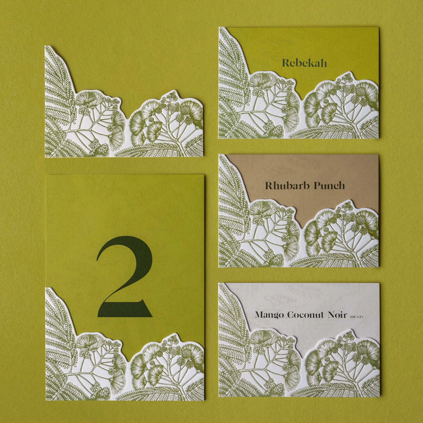 Greer and Cohen’s botanical wedding stationery featuring die-cut silk tree flower artwork across place cards, table numbers and drinks cards.