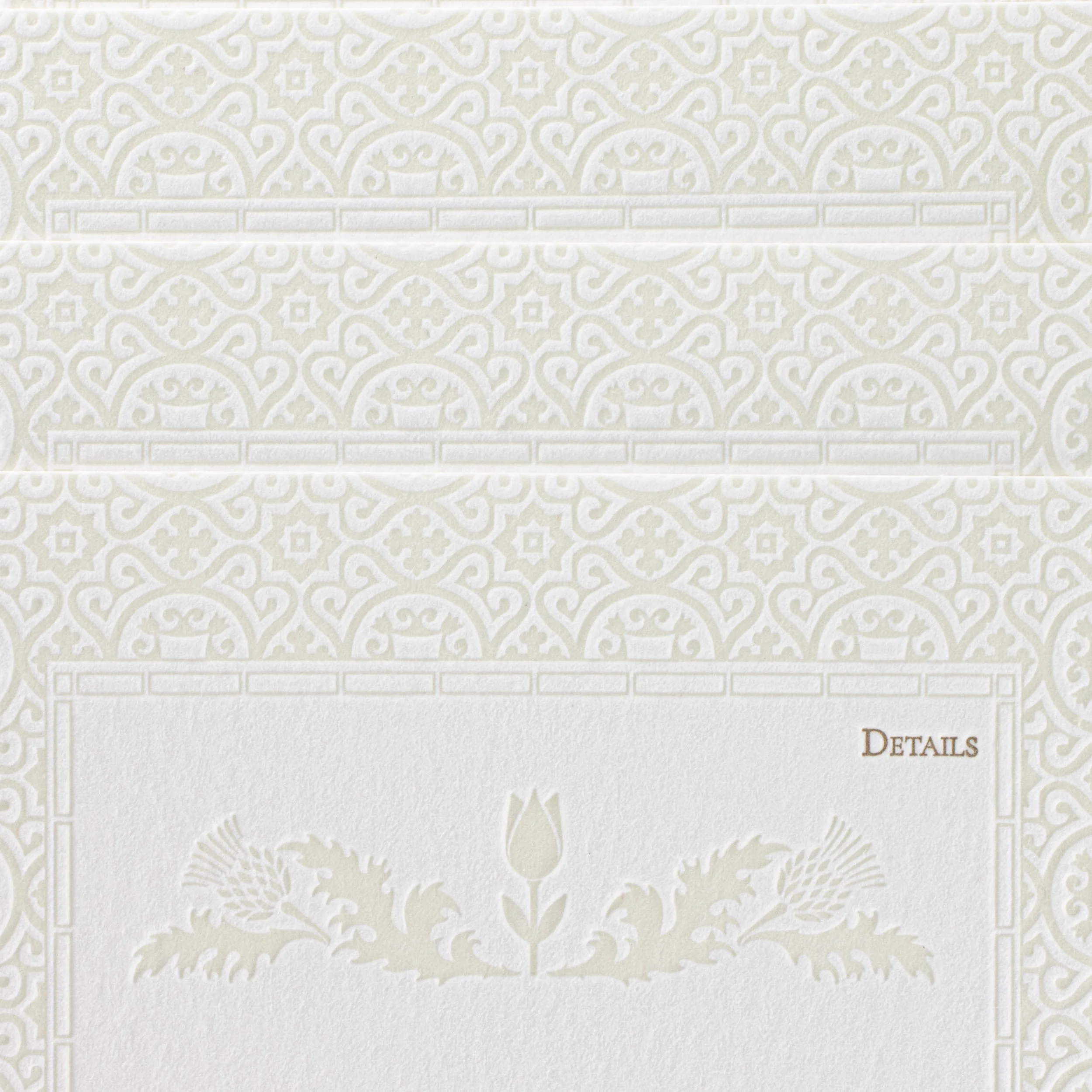 Close-up of Amy and John’s letterpress details card, with debossed tulip and thistle motifs representing Dutch and Scottish heritage.