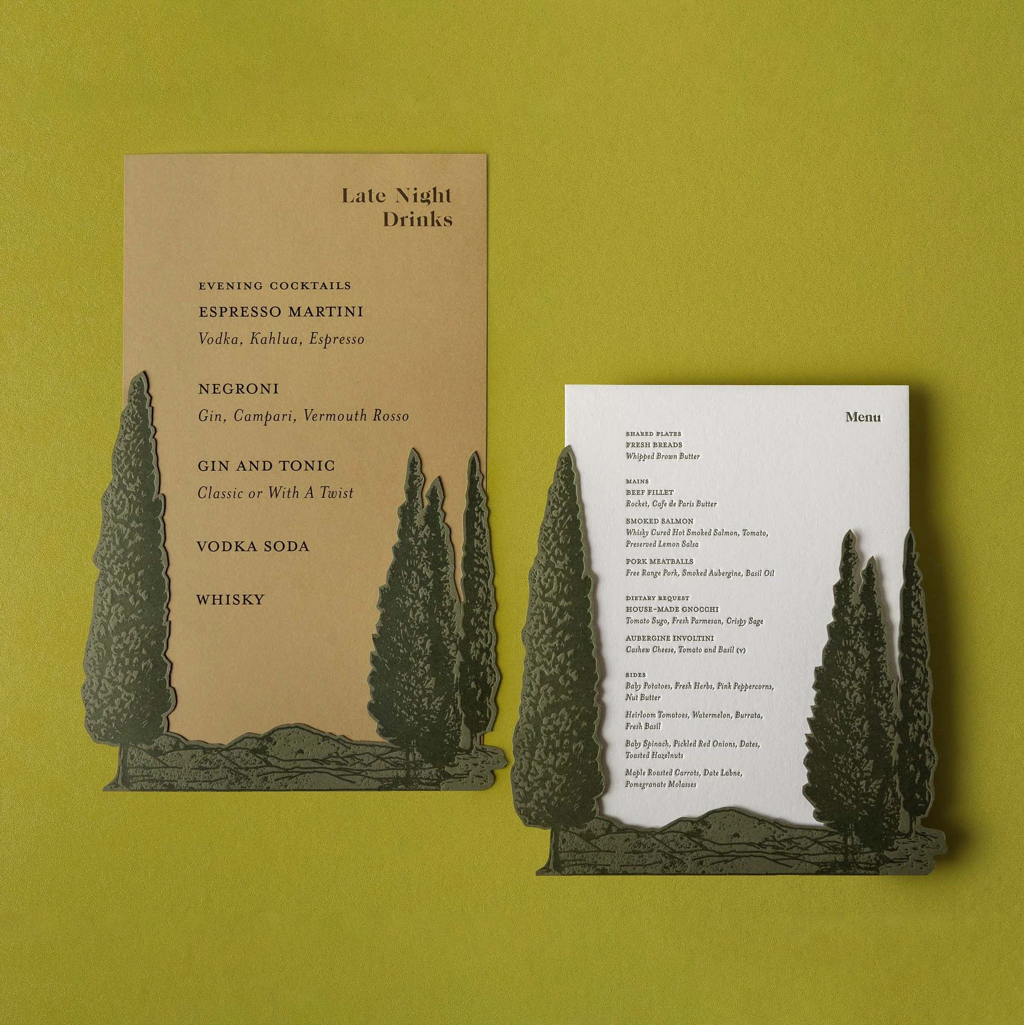 Greer and Cohen’s wedding dinner and late-night drinks menus featuring layered die-cut conifers and Mount Starveall artwork.