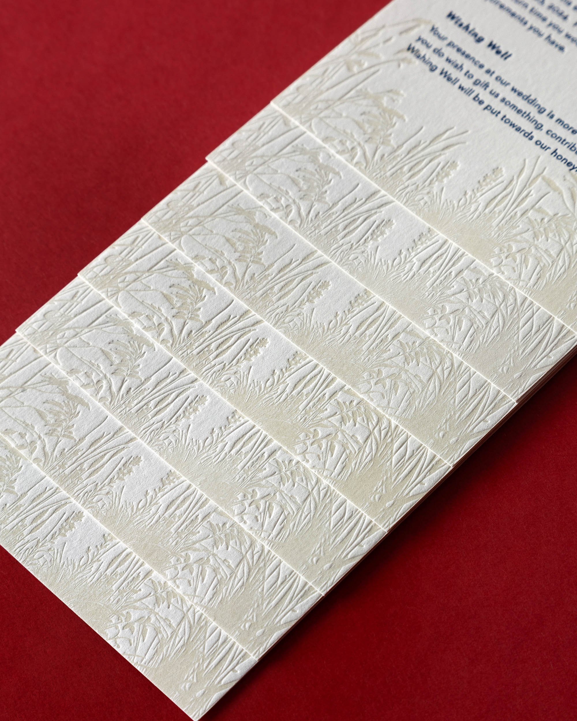 Letterpress wedding details card inspired by Boomrock Wellington’s panoramic views featuring iconic clifftop wedding arch, with burgundy and deep blue palette and modern sans-serif font.